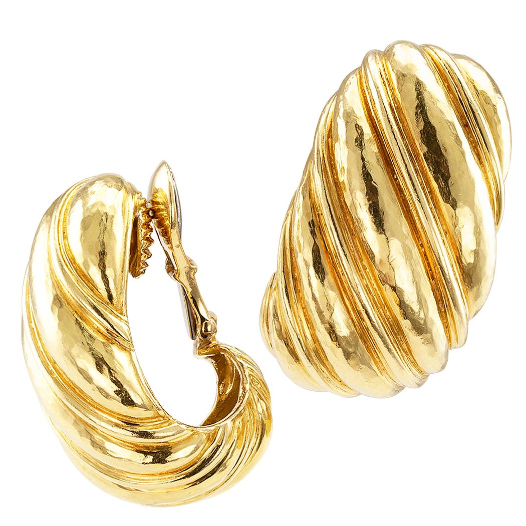 David Webb hoop gold ear clips circa 1980. Designed as a large-scale j-hoop style earring decorated with curling, deeply grooved fluted motifs and a softly hammered finish on the bright gold surfaces to capture and return light in all the right