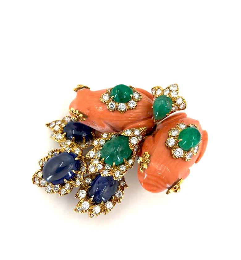 A fantastic vintage David Webb gem-set brooch in 18k gold; designed as two carved coral frogs set with diamonds and cabochon emeralds, within a spray of four diamond encrusted leaves, set with large cabochon sapphires and emeralds.

Accompanied by a