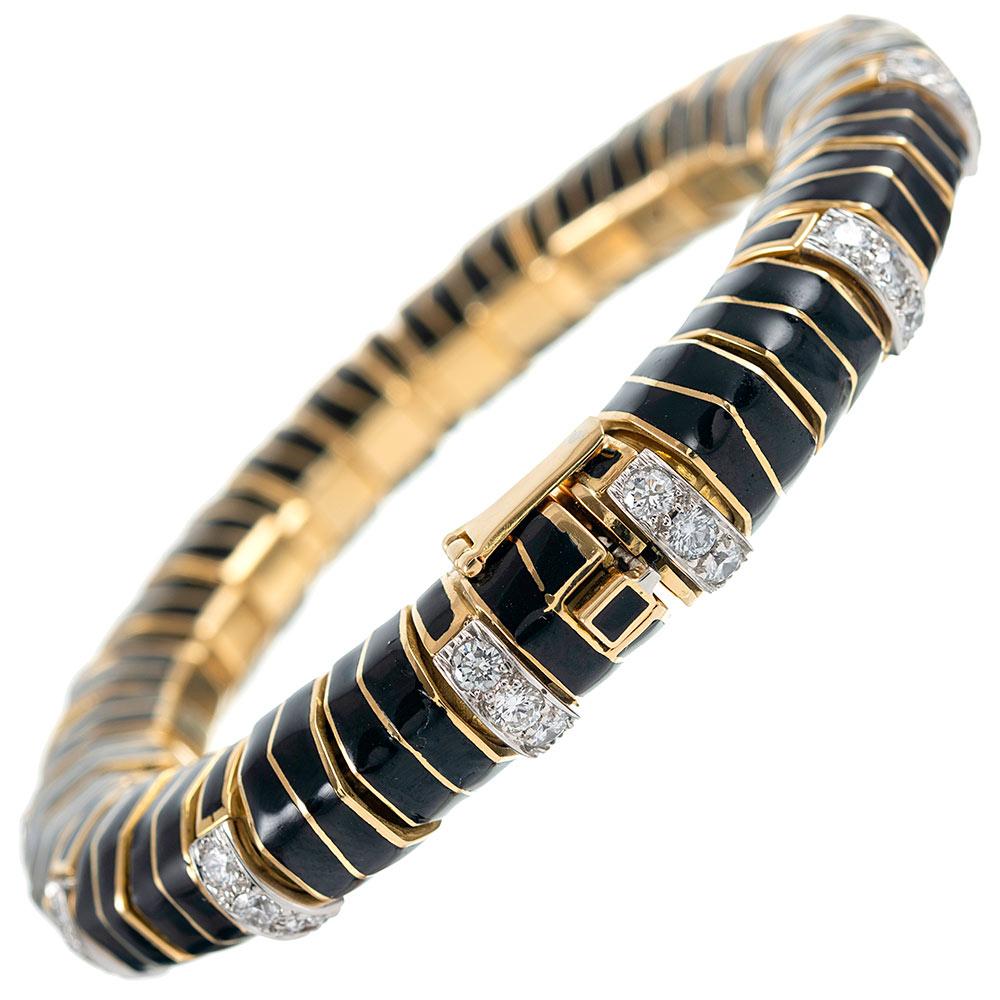 Brilliant white diamonds pop from their styled golden links against a dramatic backdrop of black enamel. The piece is gently flexible on the wrist, yet maintains its circular form. The interior diameter is 2 inches, with a half inch rise off the