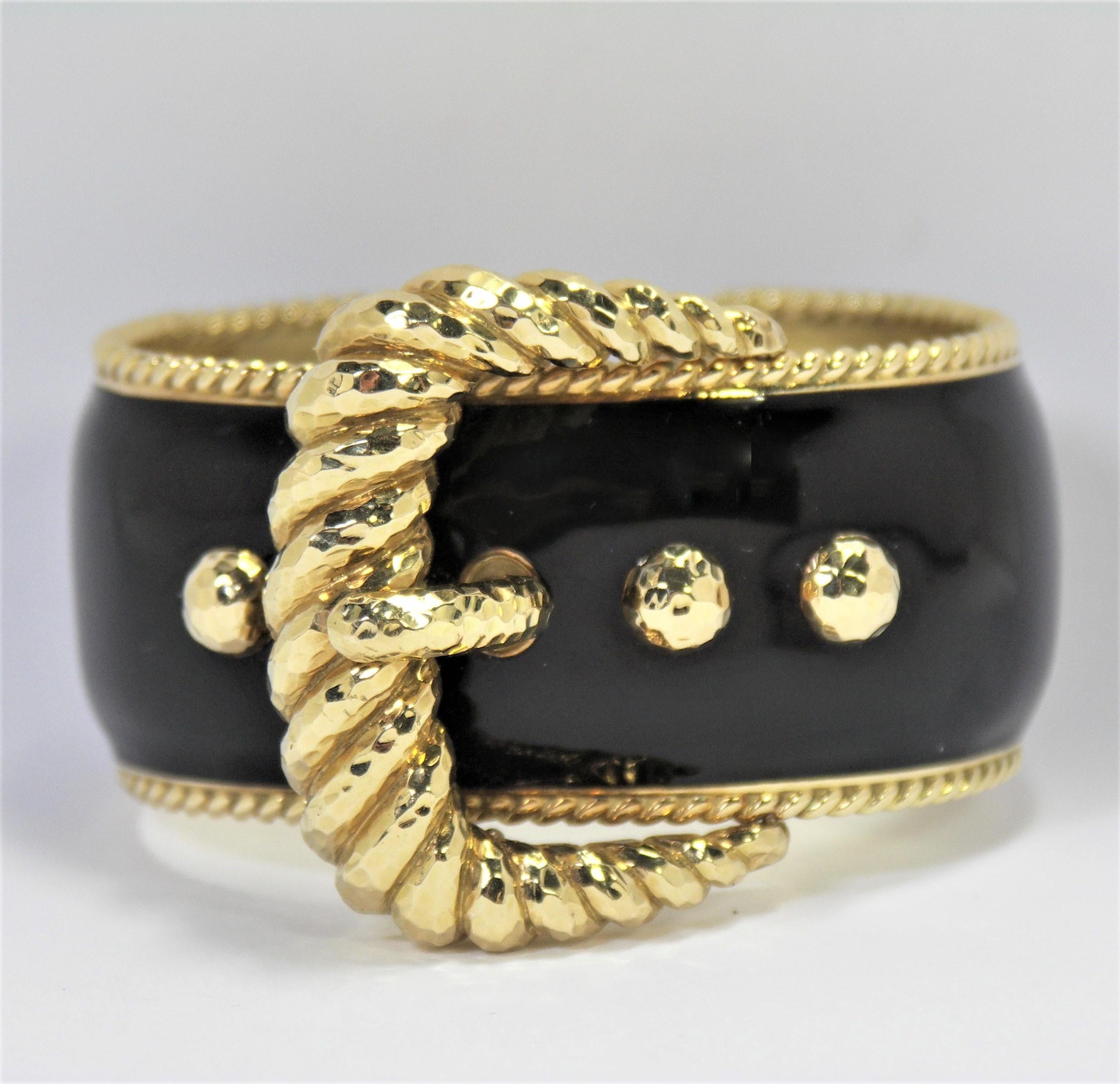 Made of 18K Yellow Gold with black enamel. this stylish bangle measures 1 3/4 inch at
the widest part of the buckle. A great addition to any David Webb collection. The locking 
hinge makes it easy to put on and to take off. Fits a small to medium
