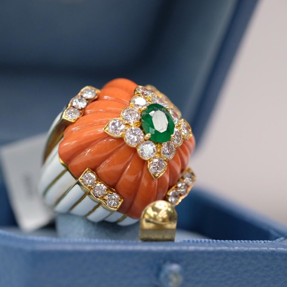 Beautiful statement ring from David Webb.

Centering upon a carved coral accented by a circular-cut diamond and cabochon emerald motif, to the polished gold bombe gallery and shoulders enhanced by white enamel, mounted in 18K yellow gold, size