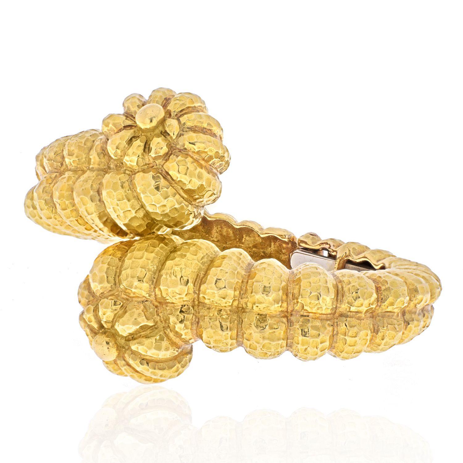 An American Late-20th Century 18 karat gold bracelet by David Webb. The hinged bracelet is composed of hand hammered gold in a dimensional crossover sea shell motif.  