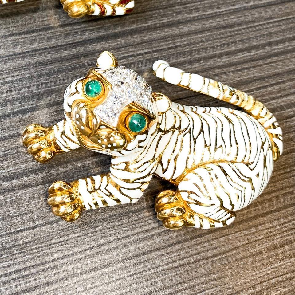 Designed as a tiger, the eyes set with cabochon emeralds, the body applied with white enamel, accented by round diamonds, gross weight approximately 41gr, signed David Webb.

In fair to good condition, the metal with light scratching commensurate