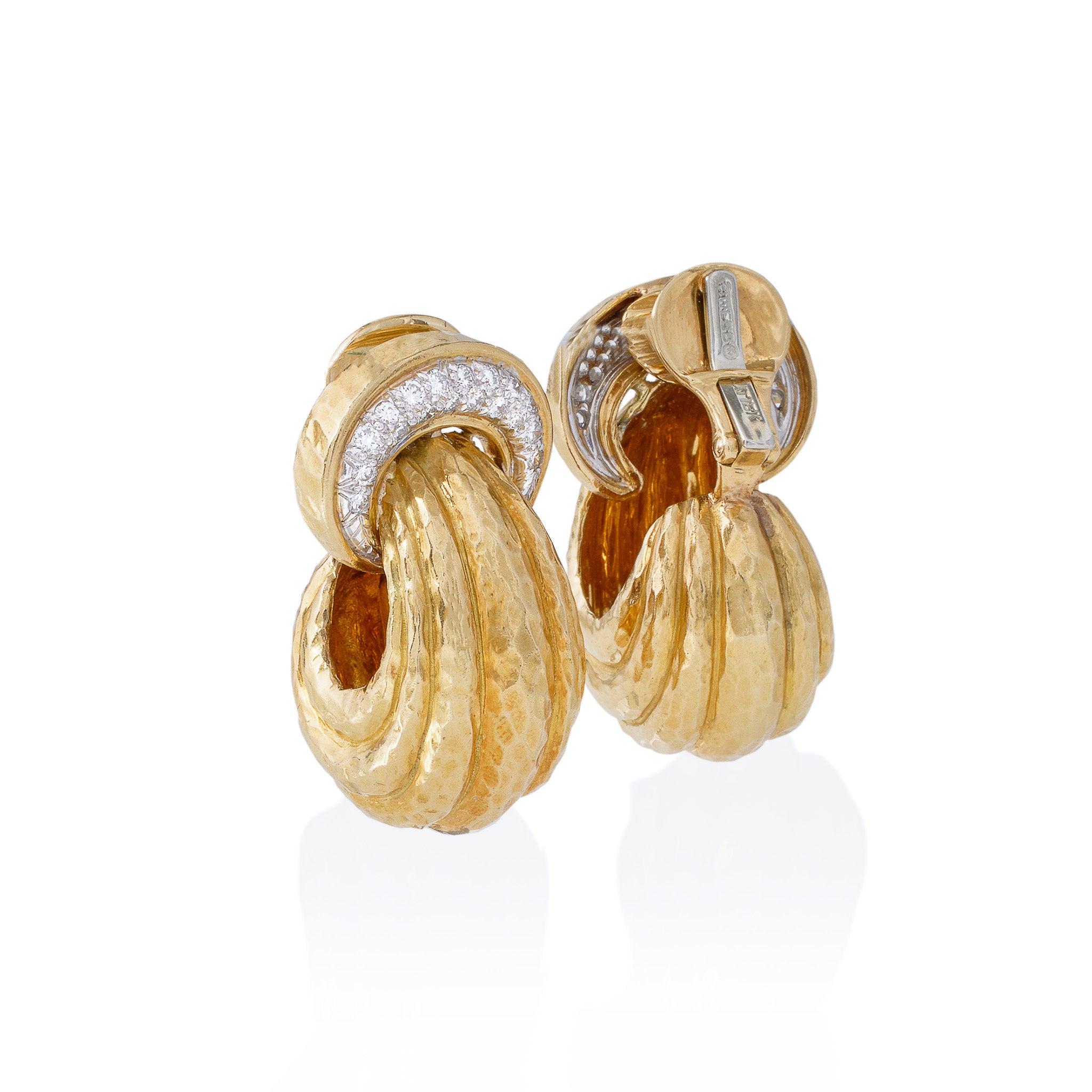 These 18K gold and diamond hoop clip earrings by David Webb, New York, date from the 1960s-1970s. Each earring is designed as a crescent form top set with round brilliant-cut diamonds flexibly suspending a broad, tapering, ribbed hoop. With their