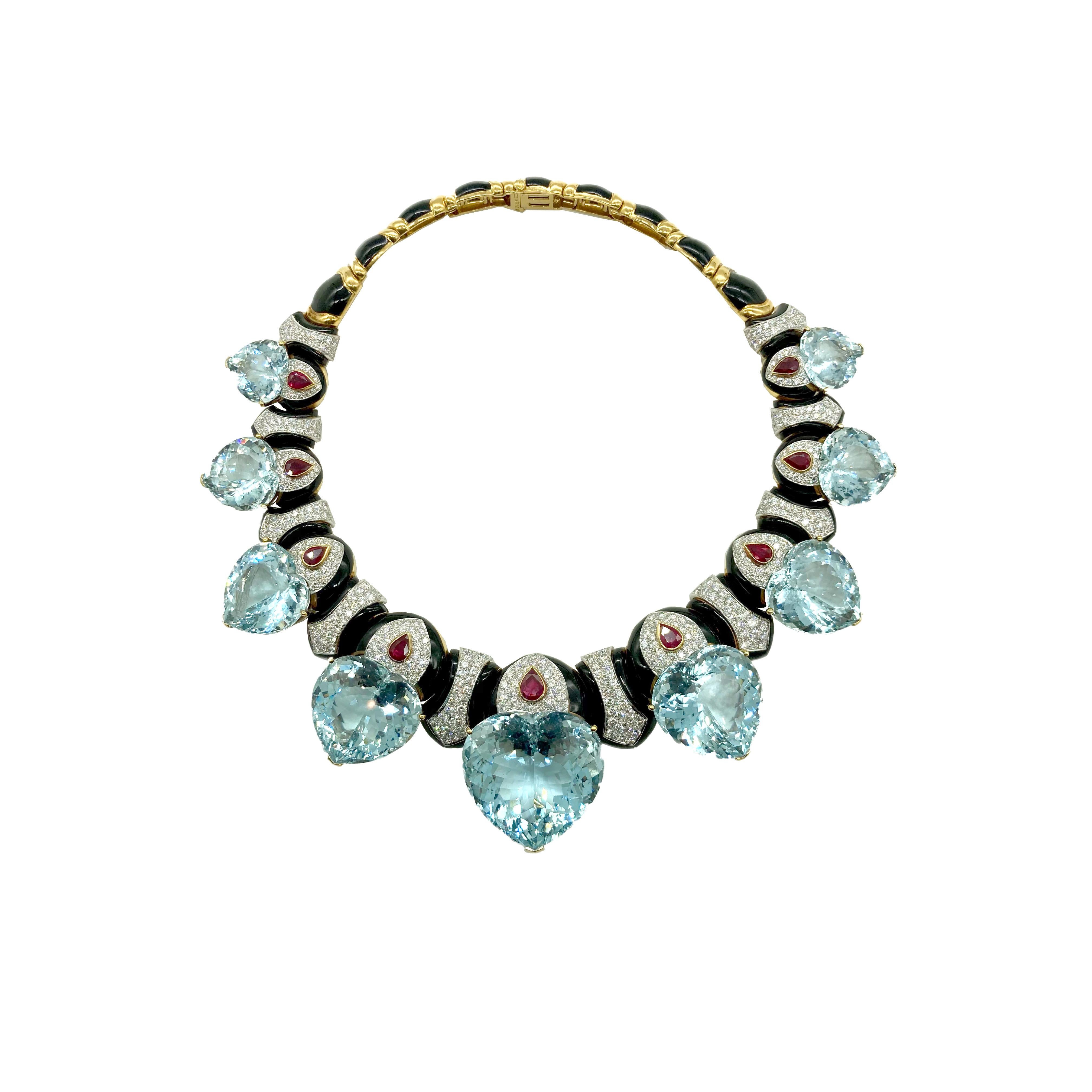 An exquisite David Webb demi-parure comprised of a necklace and earclips in 18 karat yellow gold, featuring chunky heart-shaped aquamarines, pear-shaped rubies, black onyx, and diamonds. Circa 1970.