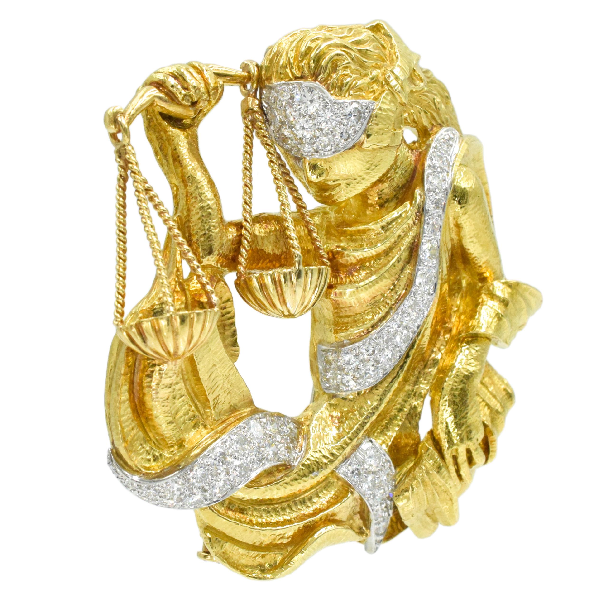 Broche Lady Justice David Webb en or jaune 18 carats et platine.  Cette broche représente Lady Justice en blinde d'or jaune 18k tenant la balance dans sa main droite, enveloppée d'une écharpe en platine
incrustée de 55 diamants ronds de taille
