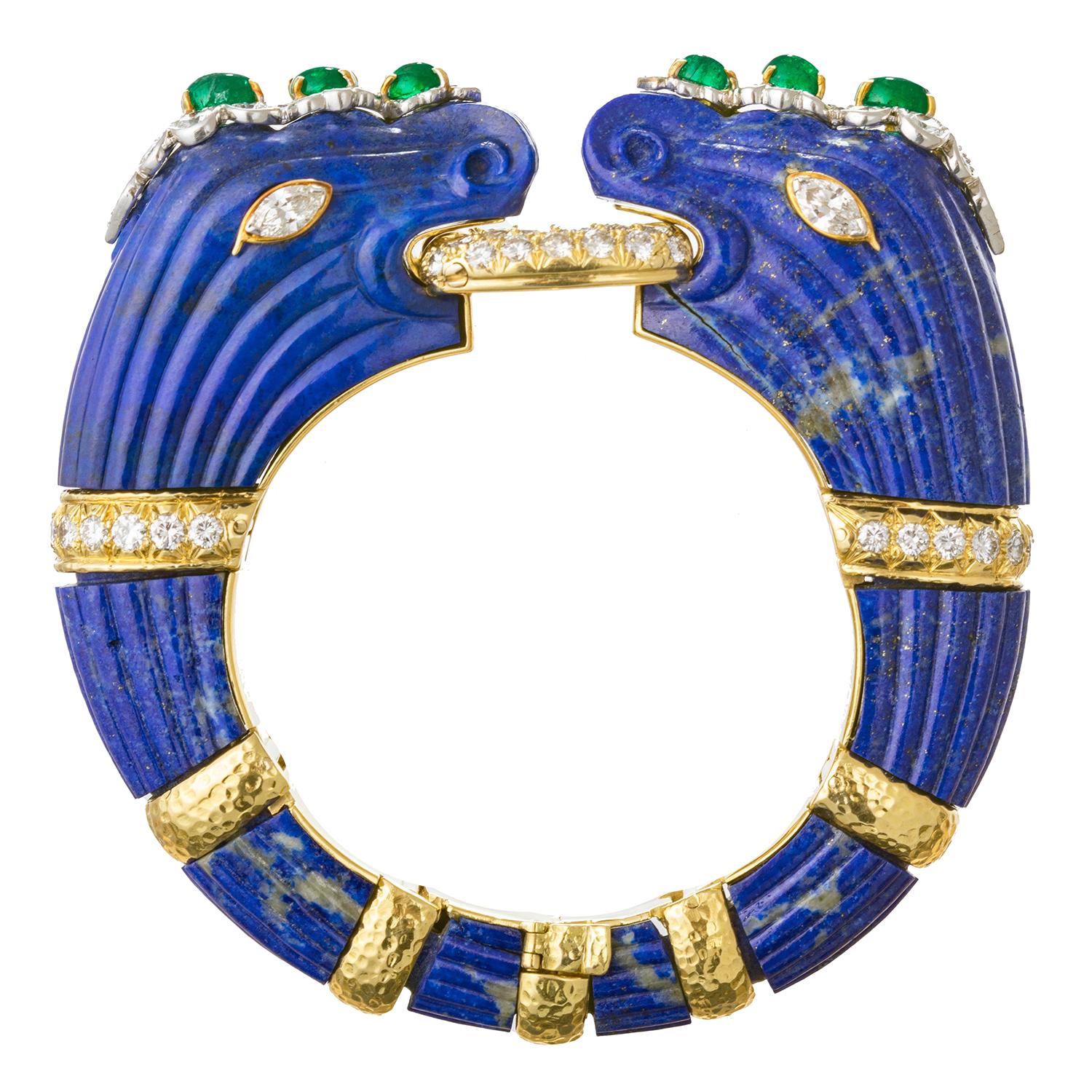 David Webb rare carved lapis double-headed chimera bracelet, mounted in 18k yellow gold with cabochon-cut emeralds and round brilliant-cut diamonds set in platinum.  Designed as an articulated hinged bangle, the two opposing lapis chimera set with