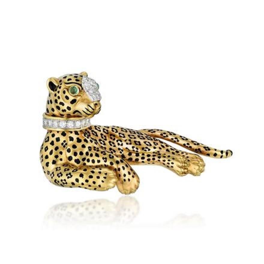A beautiful and classic David Webb animal brooch of a lounging leopard, crafted in 18k yellow gold with black enamel spots, a diamond collar and snout, with emerald eyes. 

The leopard lounges languidly, the diamond studded collar and snout dazzling