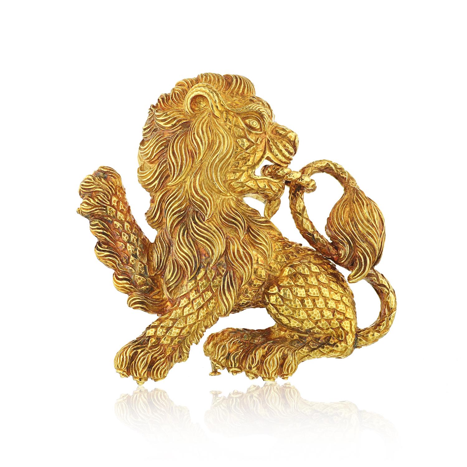 18 kt., the pawing lion biting a twisted oval link chained to its tail, decorated with detailed body and textured mane, signed Webb, approximately 71.7 dwts.
L: 8cm
W: 7.5cm
Double pin fastening. 
Can be worn as a large pendant as well.