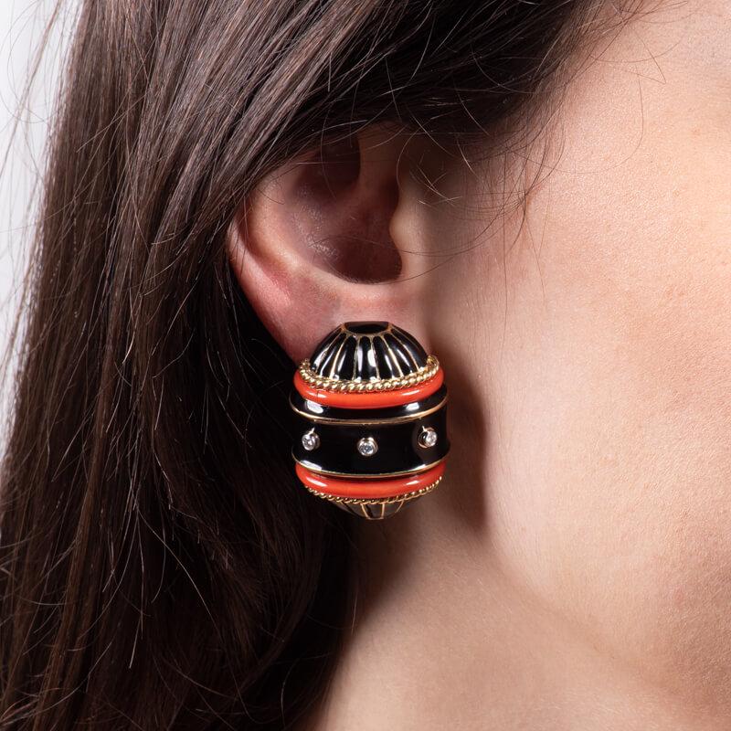 This David Webb design features earrings made with carved coral, 18kt yellow gold, platinum, 0.28ct total weight in collet-set round brilliant diamonds, and black enamel. These stud earrings are clip-ons, with an intricate lever back. They're part