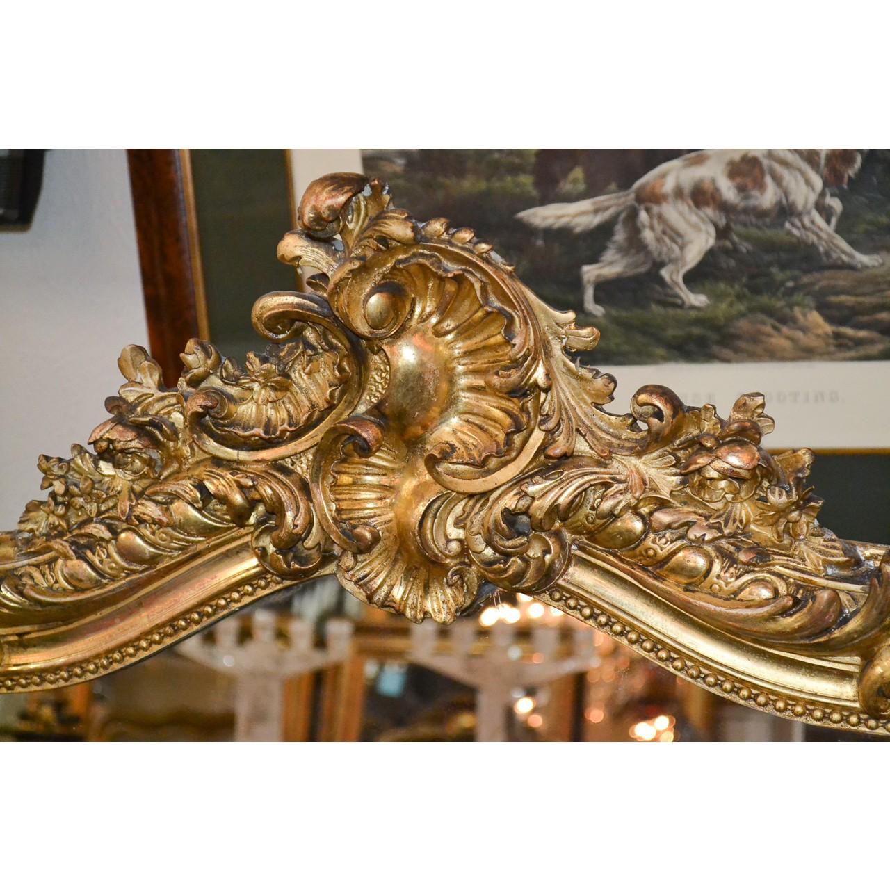 Fabulous 19th century French Louis XVI style carved giltwood wall or console mirror. The shaped crest adorned with carved shells, flower heads, and acanthus leaves. The relief carved frame and beaded inner border accented at the lower corners with