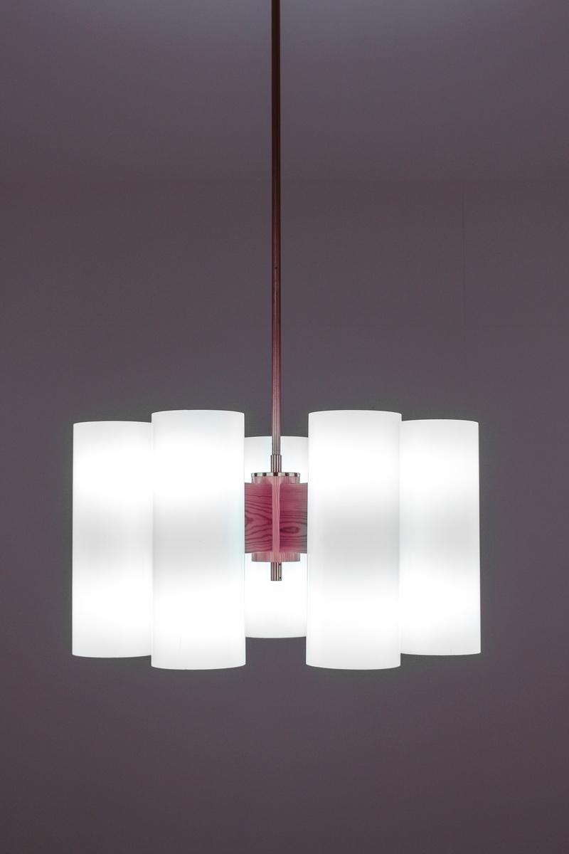 Rare chandeliers by Uno & Osten Kristiansson for Luxus. The chandeliers consist of six acrylic cylinders with two light sources in each cylinder. The cylinders are held by thick arms in pine that are fixture to the centre piece. The lamps come with