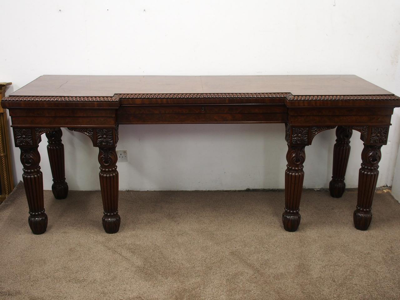 Regency inverted breakfront hall or serving table in Spanish flame mahogany, circa 1820. The inverted breakfront top is in mirror matched Spanish mahogany with a gadrooned edge above a deep moulded frieze. It has a centre drawer to the frieze, and