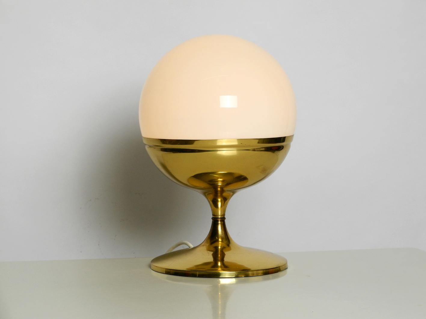 1960s extra large brass tulip table lamp with one glass ball. Great Space Age pop art design with a high quality heavy brass foot. White opal glass shade for glare-free light. Very nice condition without damages with nice patina.
Fully functional