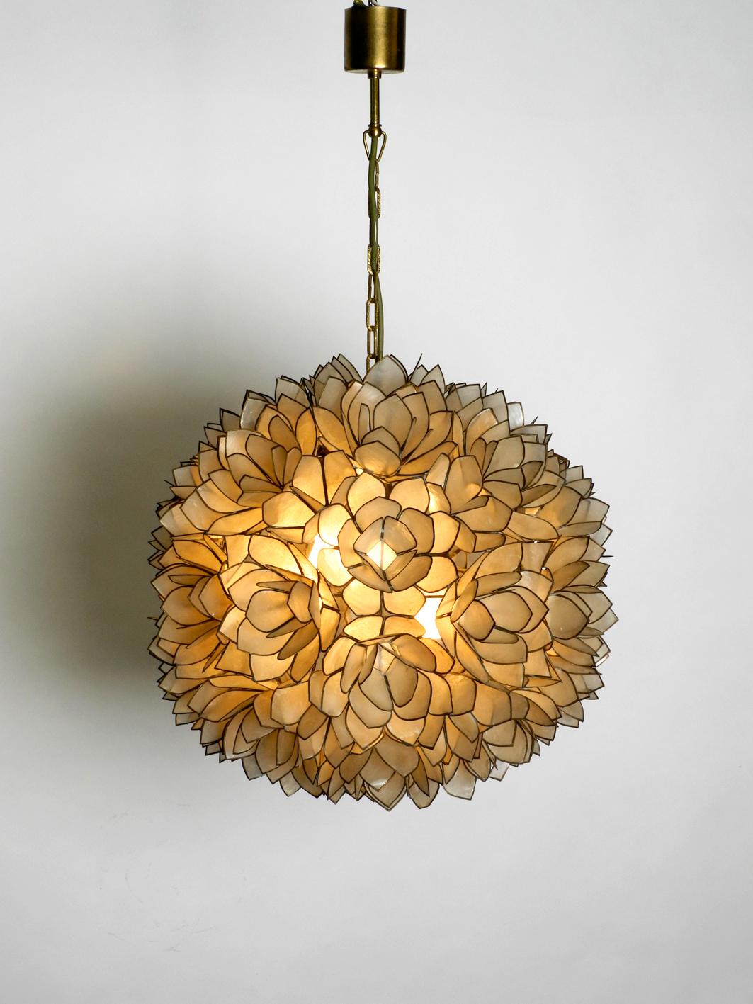 Very elegant flower pendant lamp in spherical shape made of mother of pearl. Great rare design of the 1970s. Very high quality workmanship.
Metal frame is hung on a brass chain and brass canopy. Two E27 sockets for pleasant lighting.
No damages to