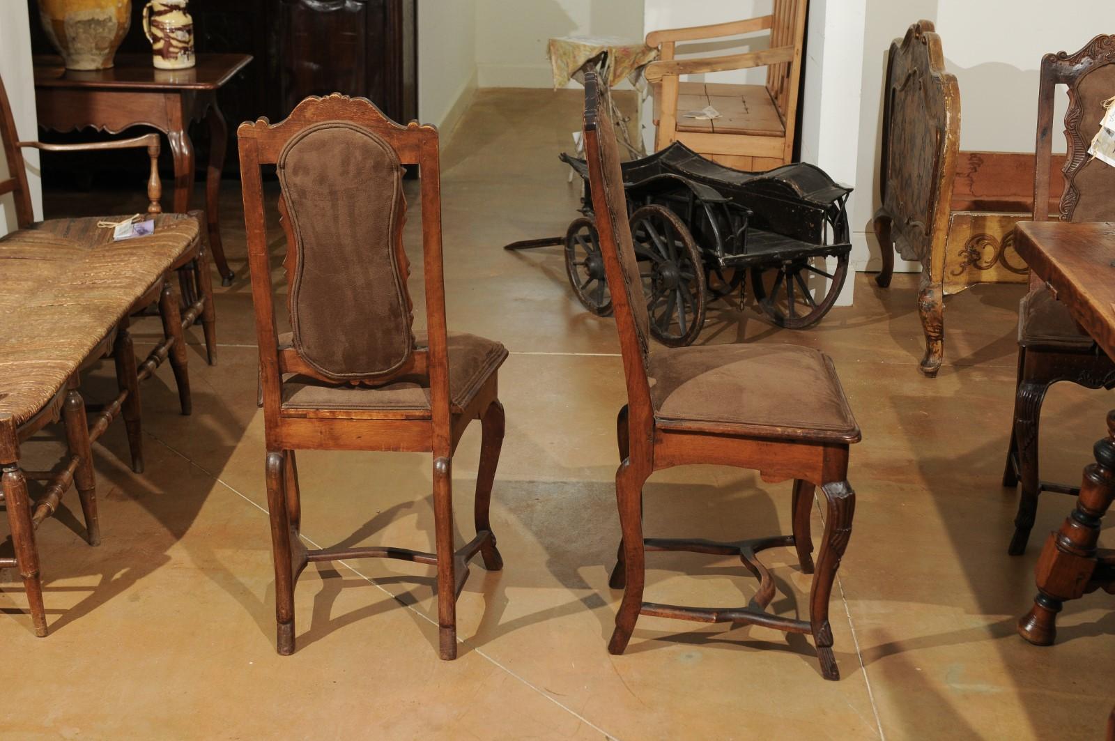 Eight Italian Roman Rococo period hand carved walnut dining room side chairs from the 18th century priced and sold in pairs, with cabriole legs, cross stretcher and brown suede upholstery. Born in the Eternal City, this collection of 18th century