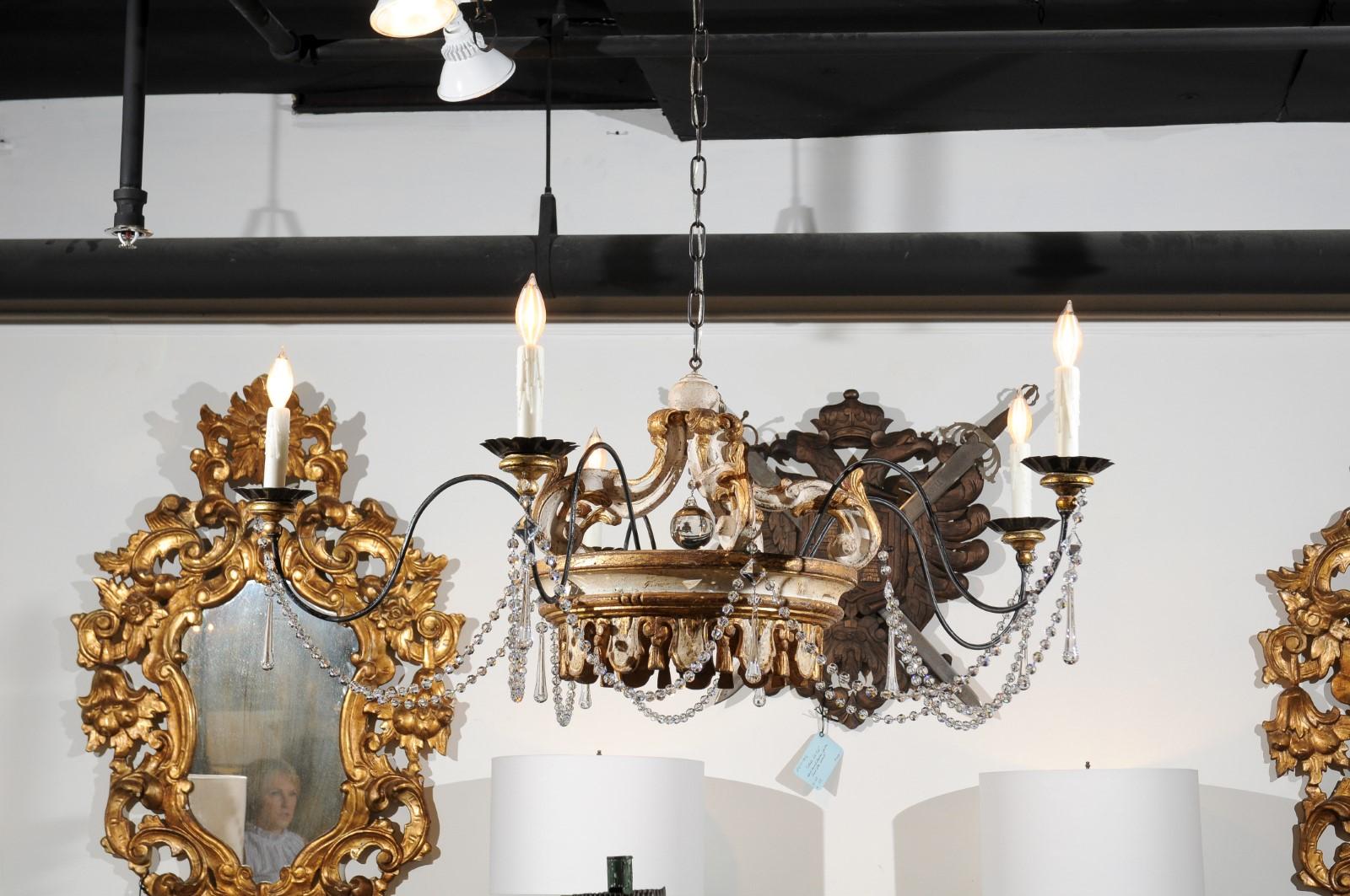 A one-of-a-kind contemporary Rococo style five-light painted and parcel-gilt crown chandelier made from 19th century Italian parts. Our eye is immediately drawn to the central Italian hand-carved crown, topped with delicate volutes joined in their