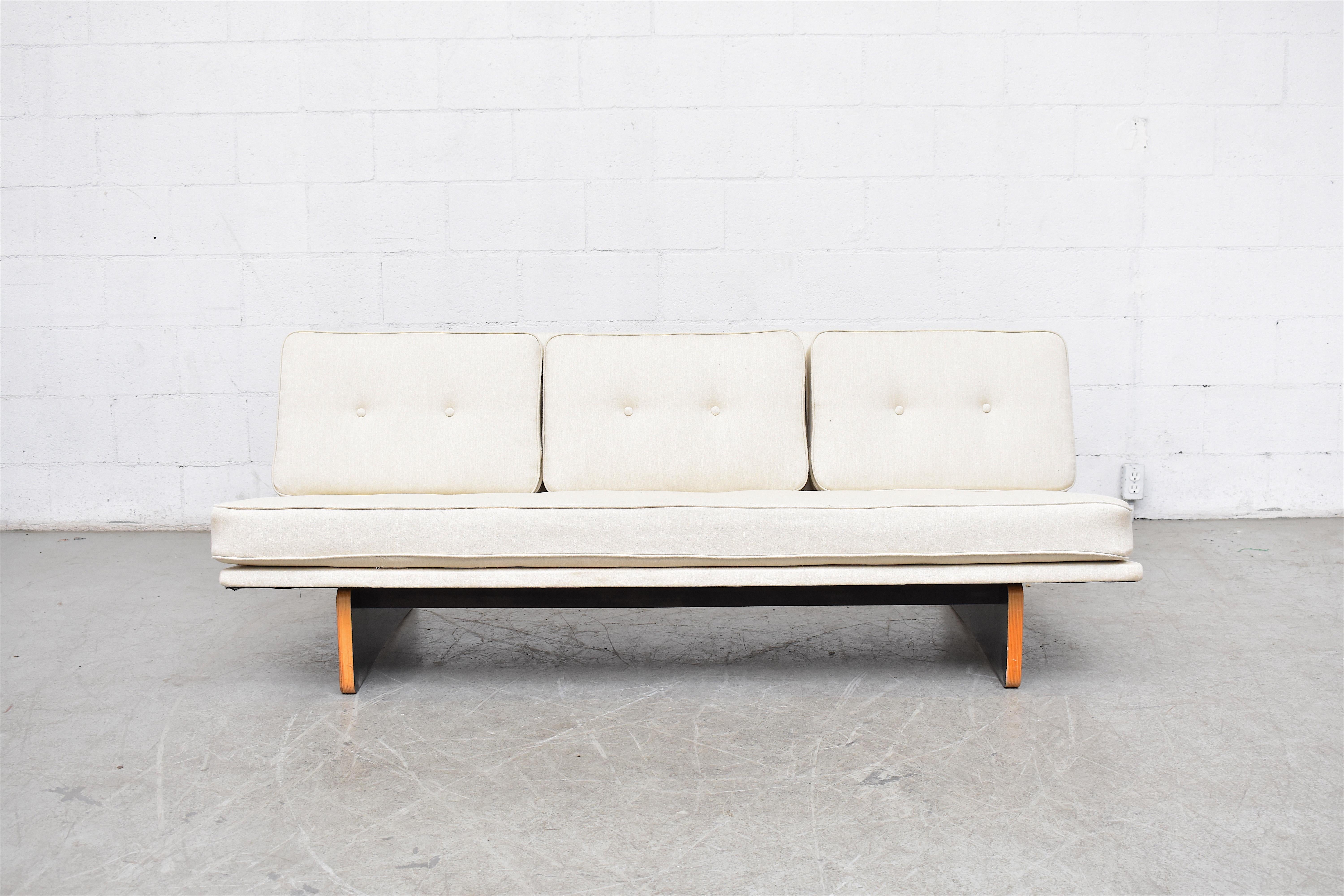 Newly re-upholstered white three-seat Kho Liang Ie sofa with rare black laminated plywood base. Base is original and shows light scratching to black laminate and wood consistent with age and use.