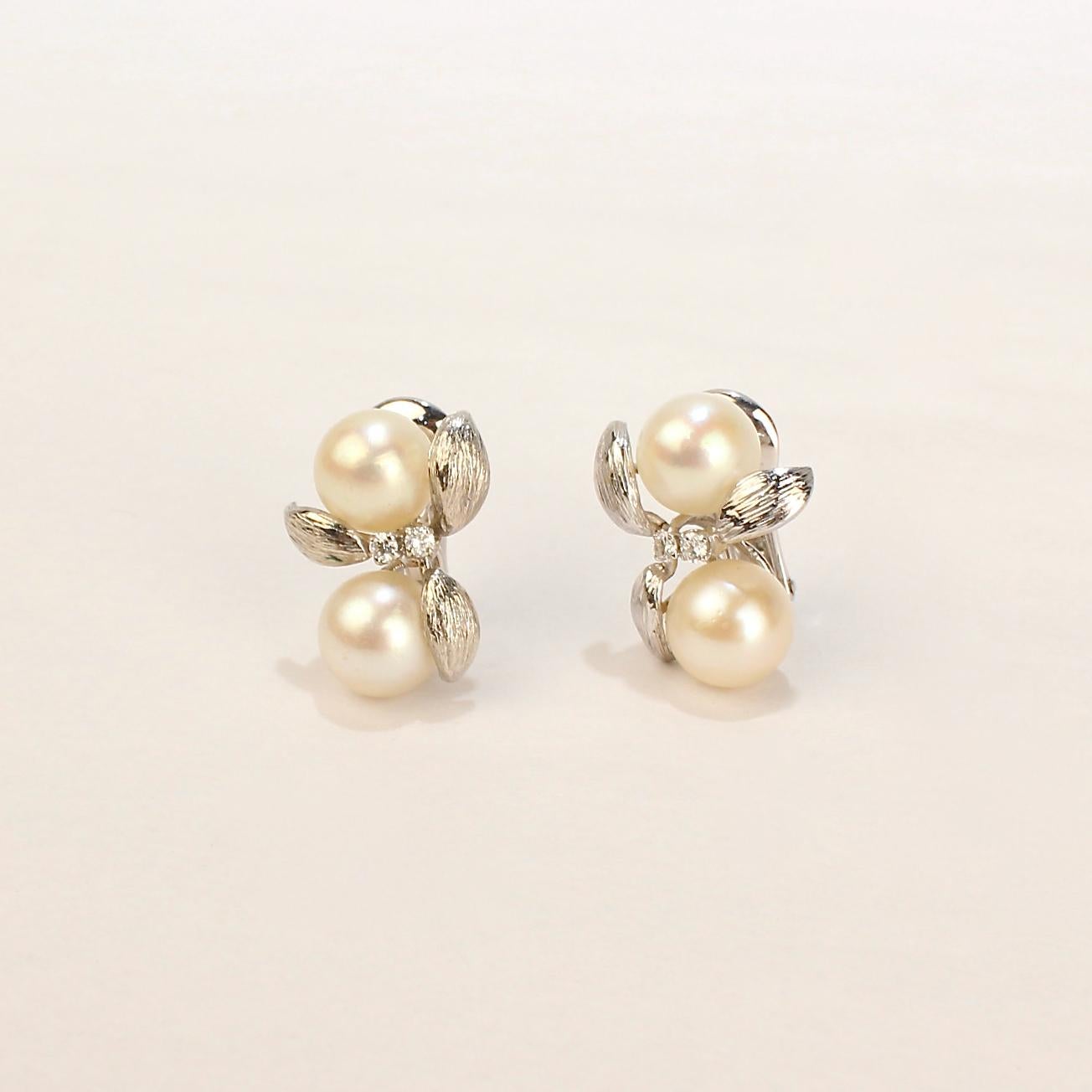 A very fine pair of David Webb clip-on earrings in 14k white gold.

Each earring with textured, stylized leaves, two ca. 9 mm round white pearls, and two small round brilliant cut accent diamonds. 

Together with the original leather pouch stamped