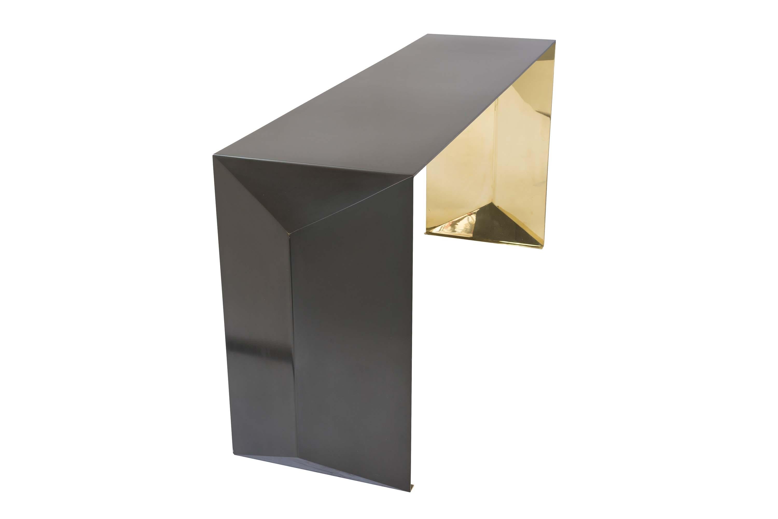 Metal console table in a hand rubbed patina finish on exterior and a mirror polished finish on interior. Marine-grade finish available at an upcharge. Inspired by folding paper and realized in sheet metal, this table's shape has a bold geometric