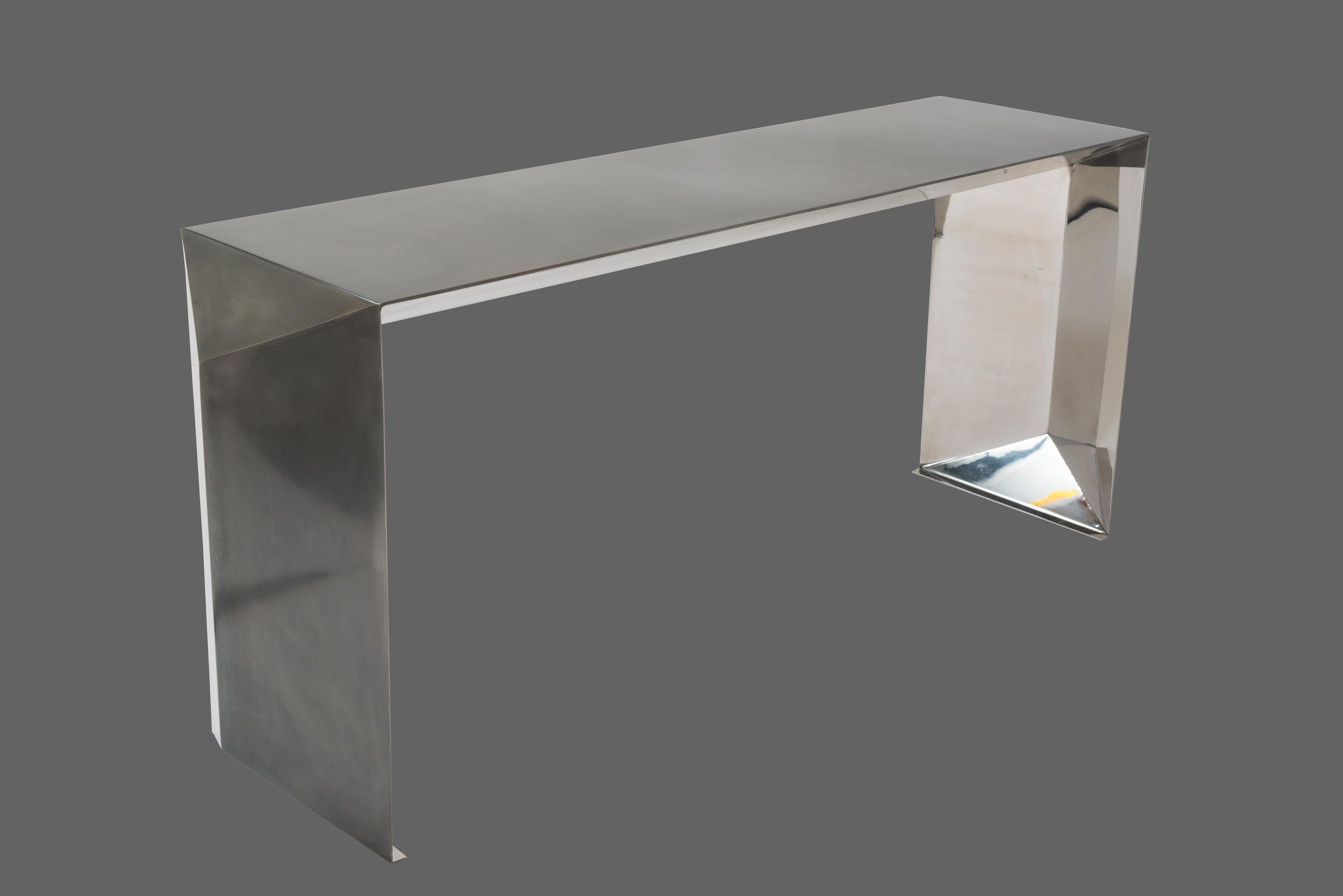 Metal console table in a hand rubbed patina finish on exterior and a mirror polished finish on interior. Marine-grade finish available at an upcharge. Inspired by folding paper and realized in sheet metal, this table's shape has a bold geometric