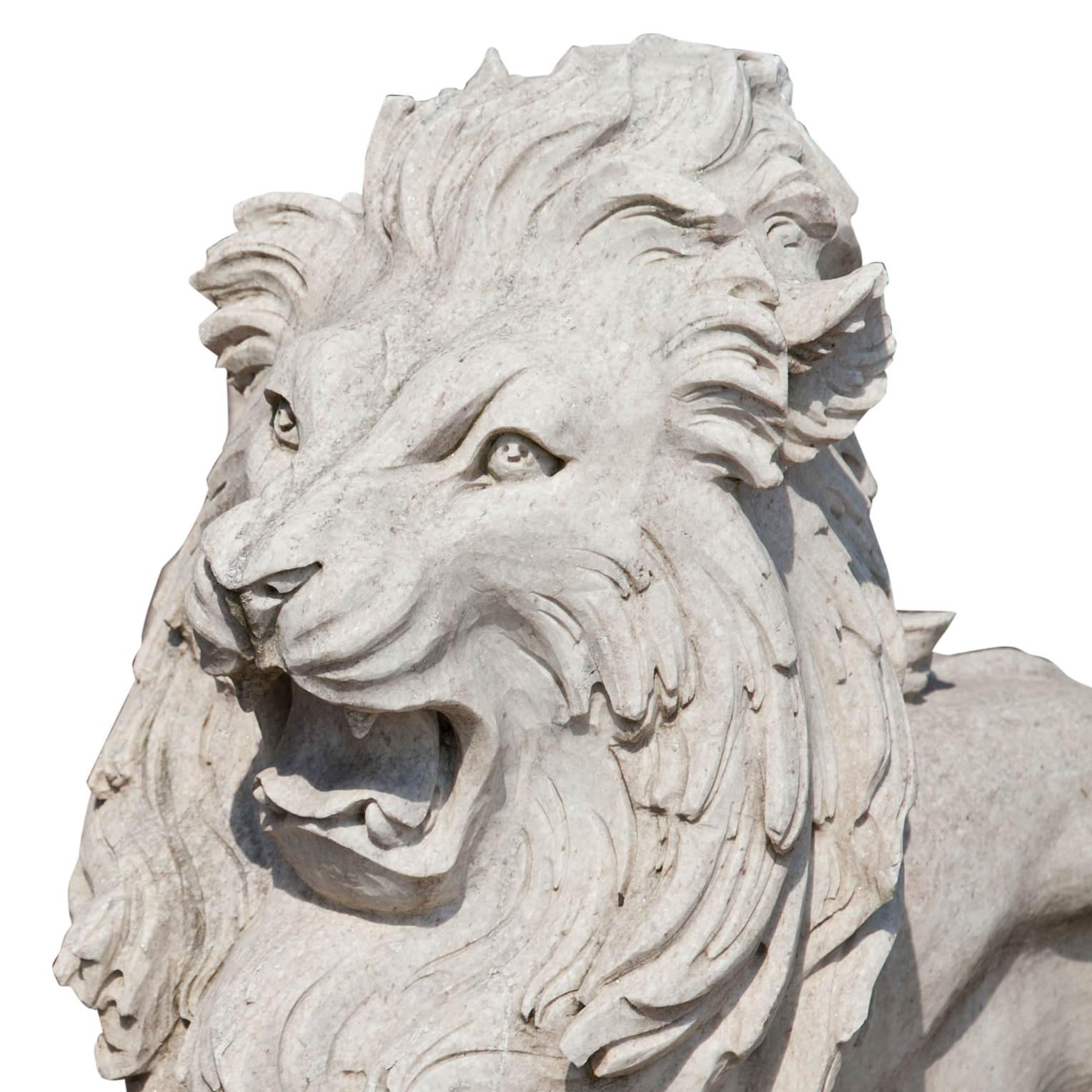 Large pair of naturalistic lions with wide-open mauls and wavy manes. The lions stand on an oval plinth and are hand-carved out of natural stone.