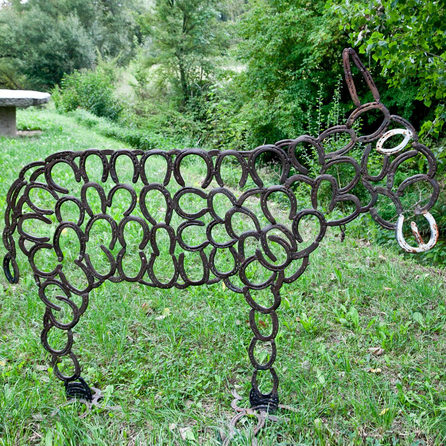 Sculpture of a donkey, made of single horseshoes, welded together. The eye and maul are painted white.