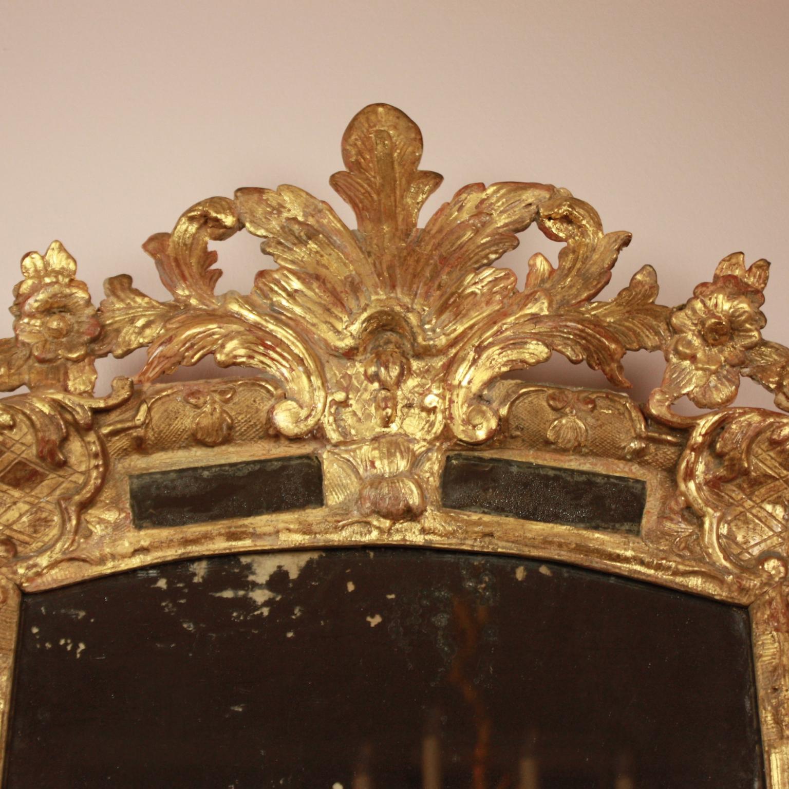 French Early 18th Century Régence Gilt and Carved Wood Mirror

An early 18th century Régence giltwood mirror of slightly arched shape surrounded by marginal mirror plates on all sides set within enriched mouldings. The giltwood cresting of acanthus