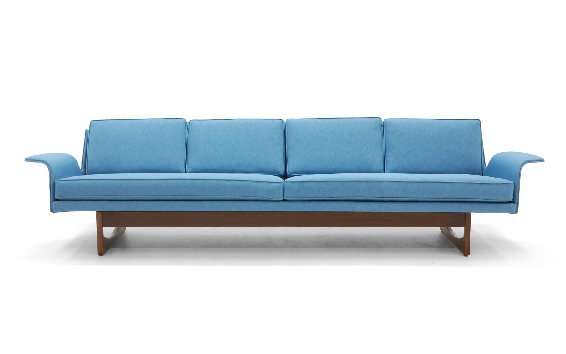 Nine feet long, four-seat sofa completely restored and in a beautiful sky blue / medium blue durable cotton and polyester fabric. We don't know if this is Danish or possible an Adrian Pearsall design for Craft Associates. The bent wood arms are
