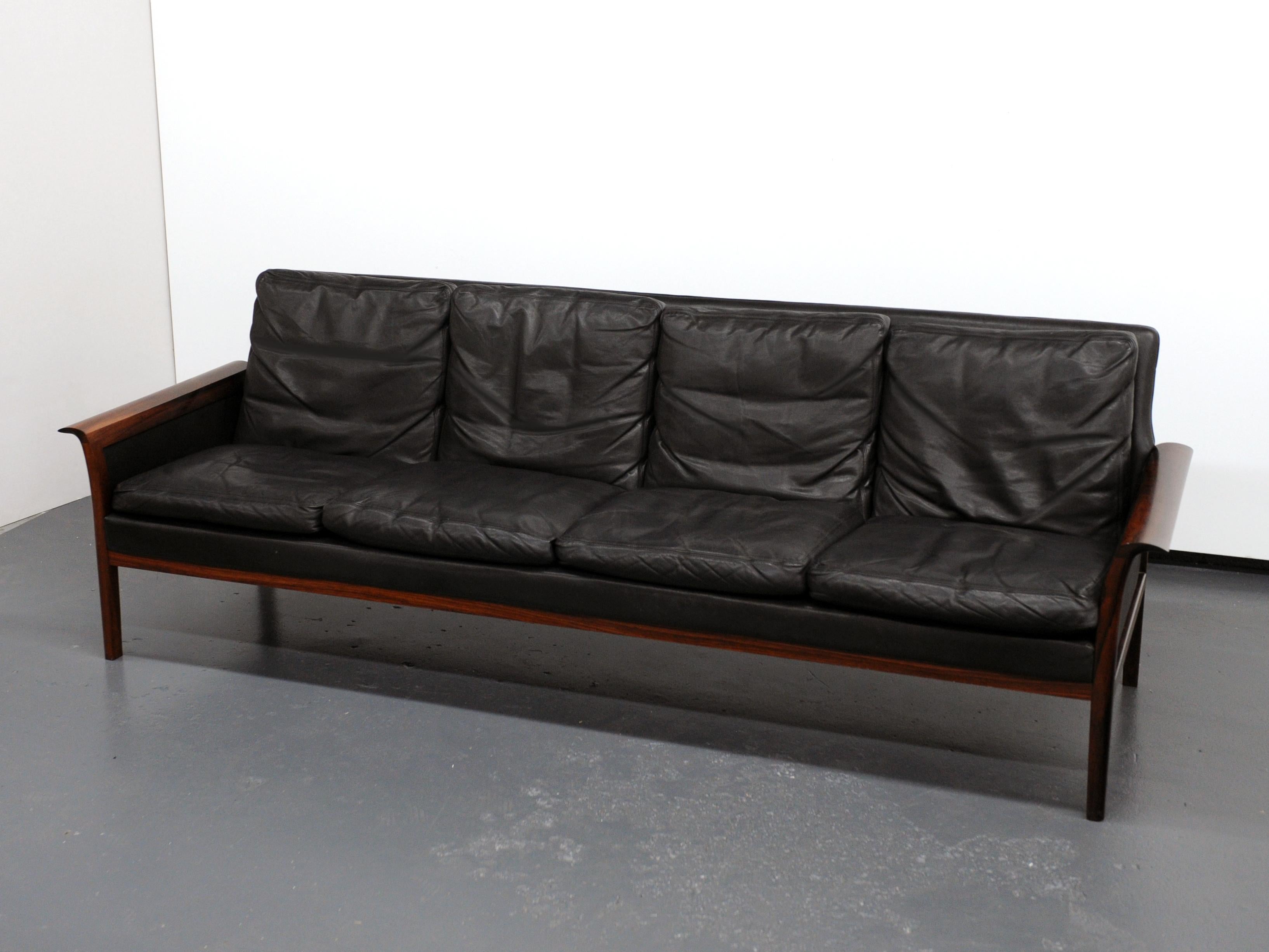 Attractive and well made four-seat sofa in black leather with solid rosewood frame. Desirable design with beautiful curved rosewood armrests. Manufactured in the 1960s by Vatne Møbler of Norway, label to underside. Soft black leather with original
