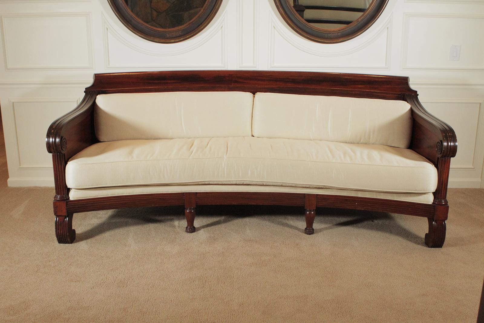 Mahogany Regency style sofa. The gorgeous hand carved frame with pillow back and seat. The fabric is somewhat worn and will need recovering. A very rare and long 97' inches long and gently curved. Dimensions: 97 W x 40 D x 39 H.