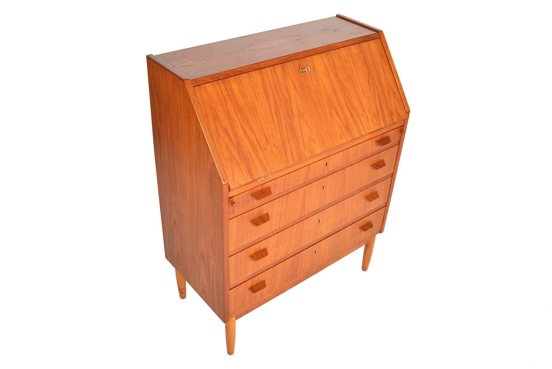 This compact Danish modern teak secretary offers beautiful angles and impressive storage. Drop- down door is supported by two felt- lined runners and reveals a writing surface with eight small drawers. Four lower drawers with brass escutcheons