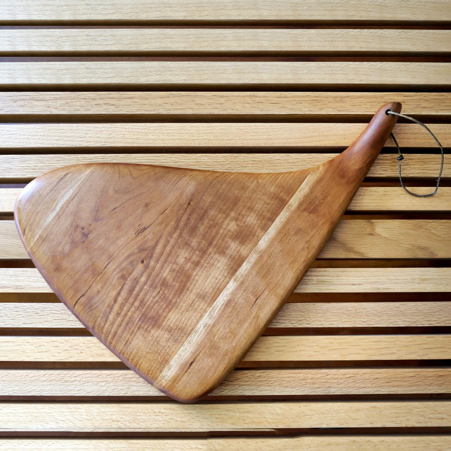 Beautiful carved wood cutting or serving board by Dean Santner. 

Dean Santner – East Bay designer-craftsmen know for his finely crafted line of wood products from the late 1970s and 1980s. 

From Santner promotional material: “Every design is