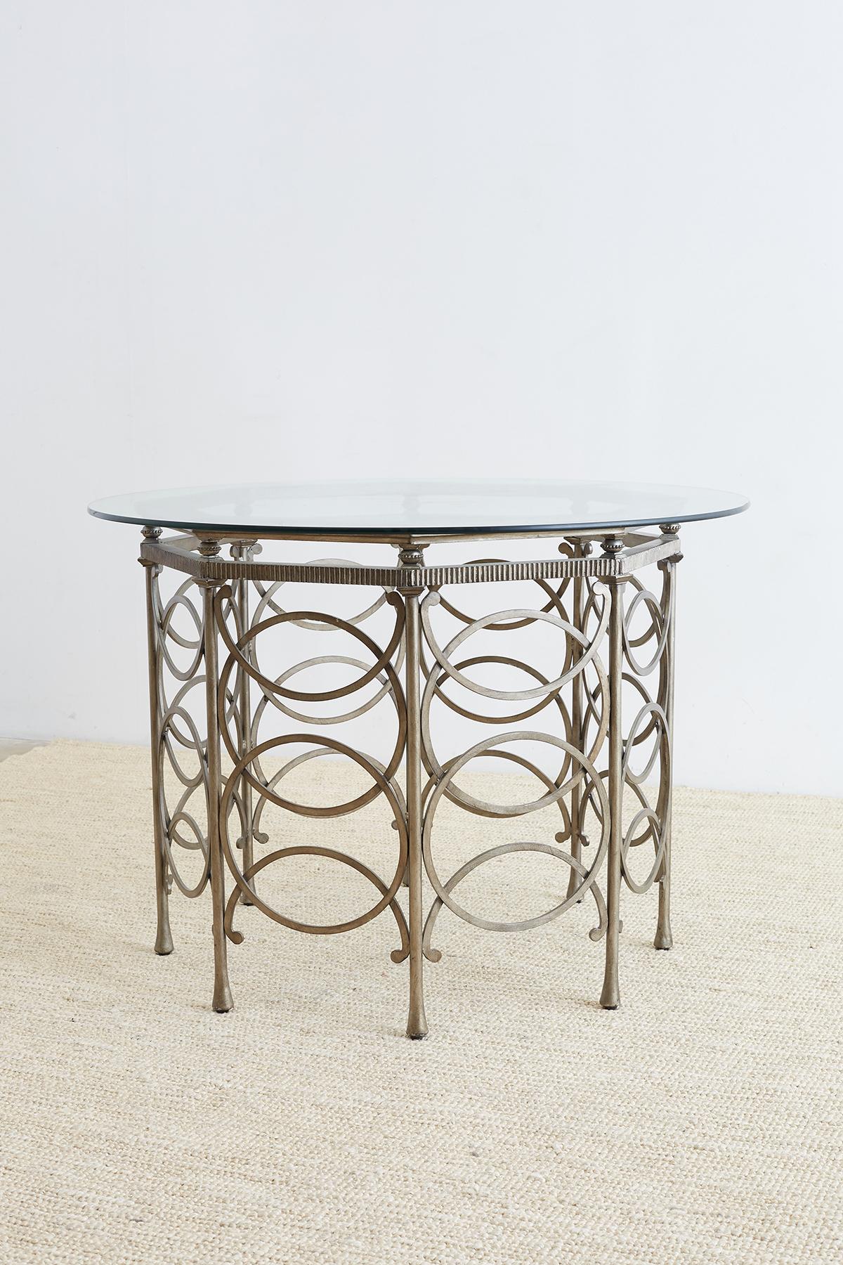 Exceptional round silver metal base dining table or center table decorated in the neoclassical taste. Features an octagonal metal base with eight legs accented with rings and demilune motifs. Each thick column leg connects to a reeded stretcher