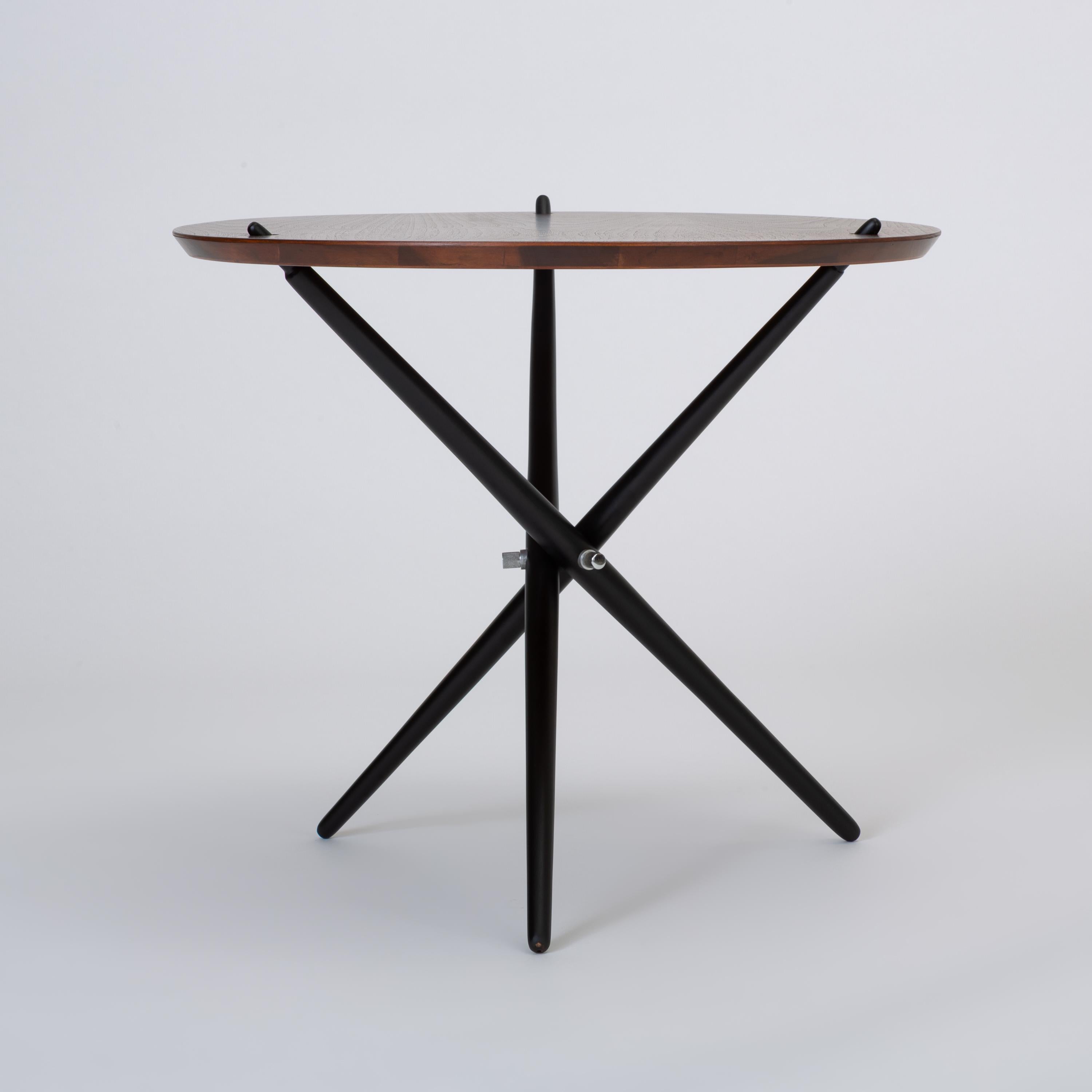 Designed by Hans Bellman for Swiss retailer Wohnbedarf, the model 103 side table was introduced to the US market in 1948 by Knoll Associates. The small round table features a tripod base of three tapered dowels, painted black and gathered where they