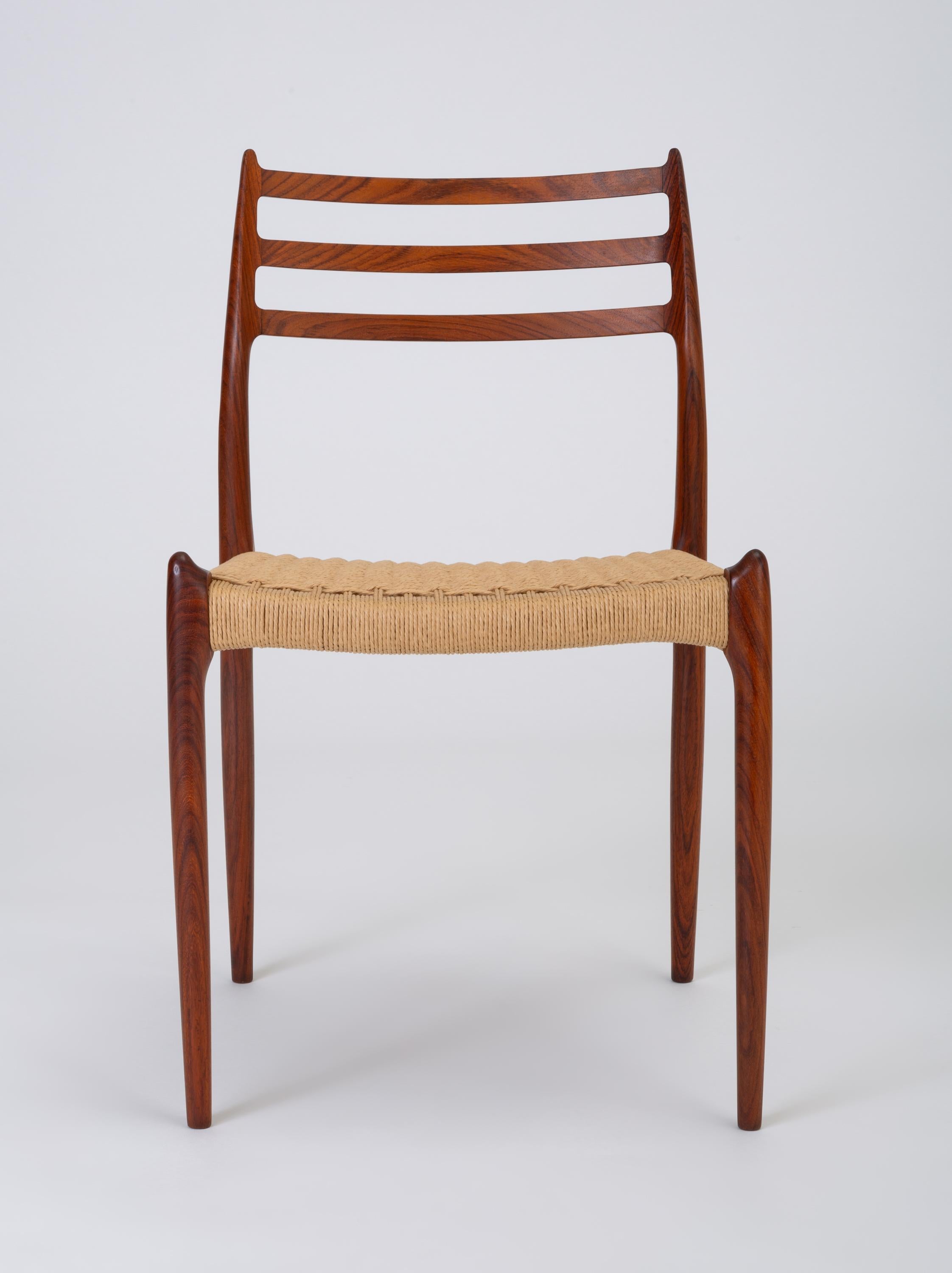 A set of six rosewood dining chairs designed by Niels Otto Møller in 1962 and manufactured by JL Møllers Møbelfabrik of Denmark with Danish [paper] cord seats. The chairs have a curved backrest with three horizontal supports, terminating in a