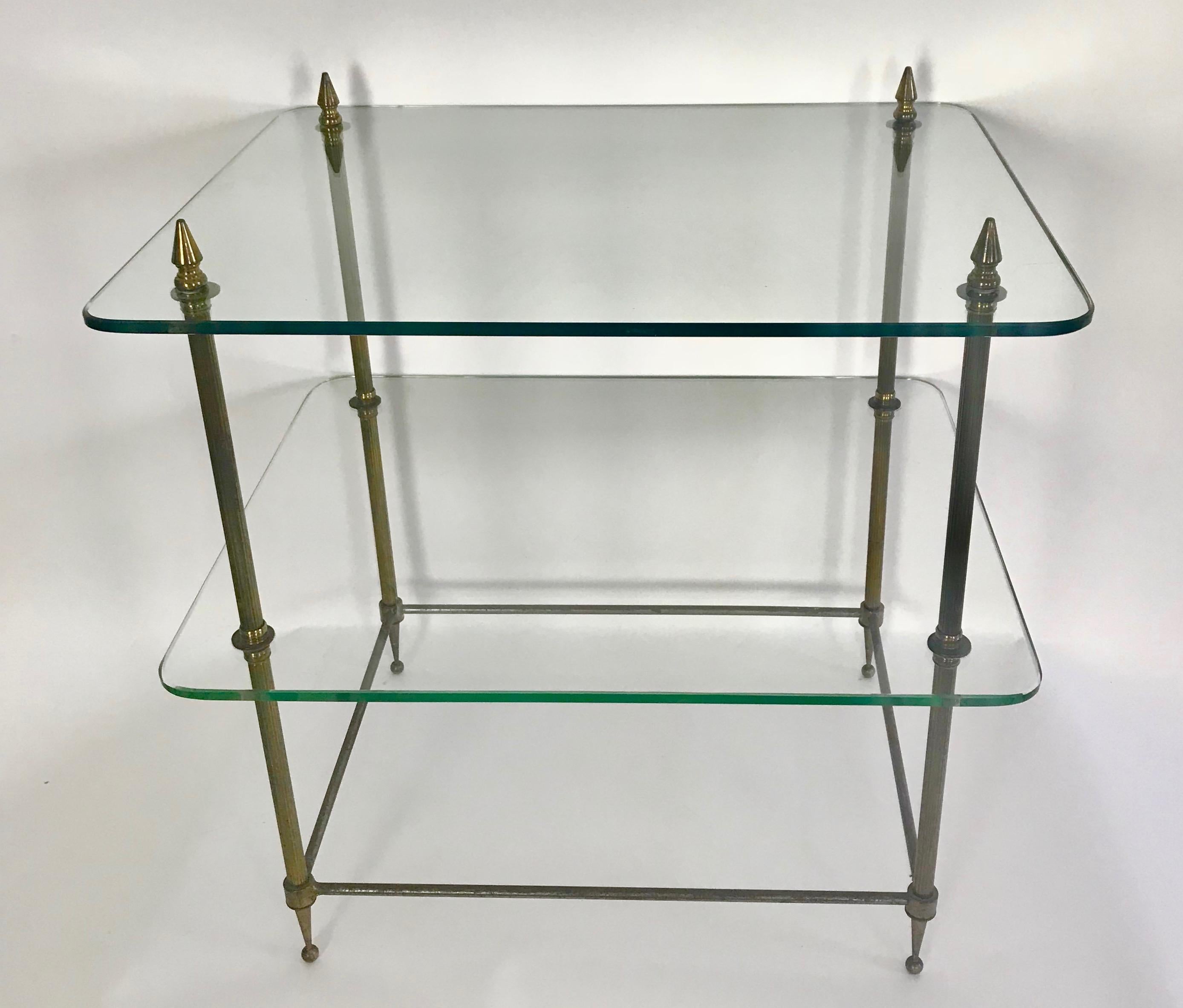 This is an early 20th century two tiered glass and brass side table from France.