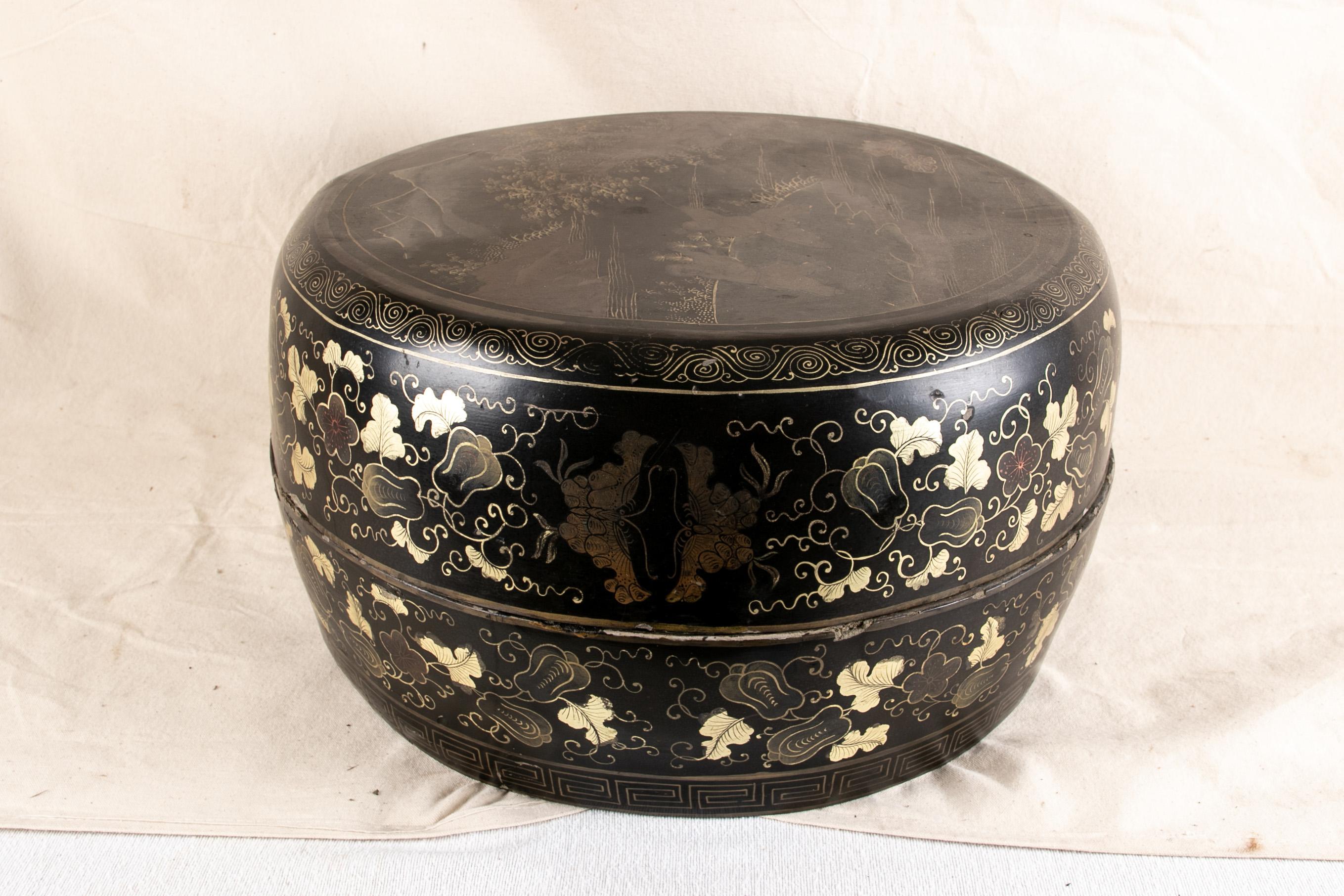 Large antique oriental lacquered and decorated box, circular box in black lacquer with white, kpurple and gilt decoration, lid depicting two children flying a kite against a forest landscape with mountains in the distance, sides decorated with leafy