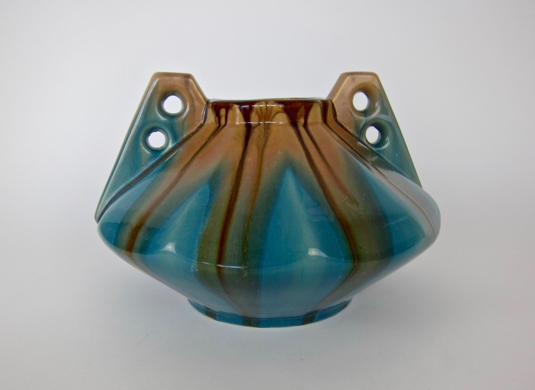 A large and sculptural Art Deco vase, made by Faiencerie Thulin of Belgium, circa 1930s. The vintage art pottery vessel was designed with a striking and angular Art Deco profile accented with with two buttressed handles and a glossy teal blue outer