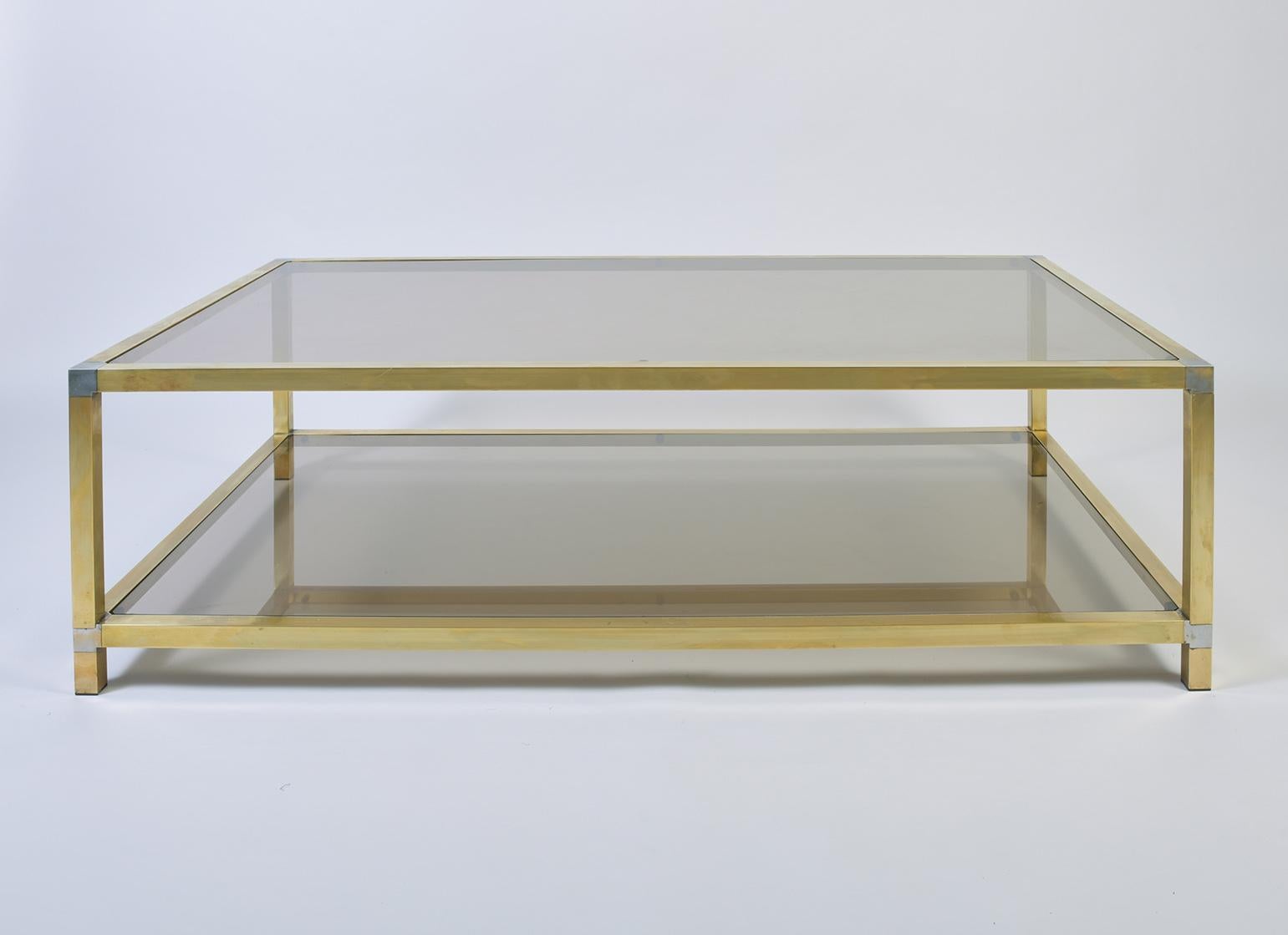 A large brass and smoked glass two-tiered coffee table, with silvered corners
France, circa 1970.