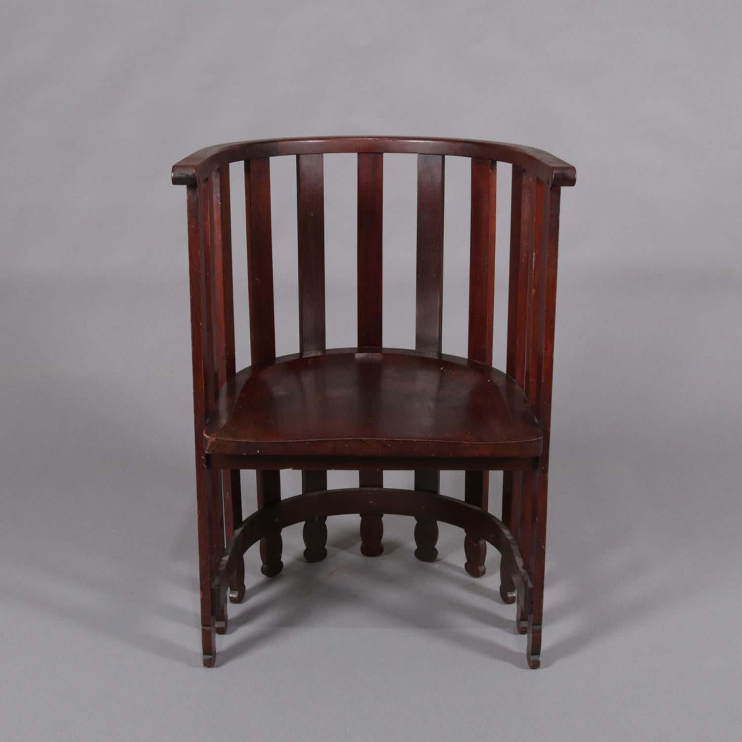 Arts & Crafts Frank Lloyd Wright Prairie school armchair features mahogany construction with barrel back form and having spindles with shaped feet, 20th century.

Measures: 31.25