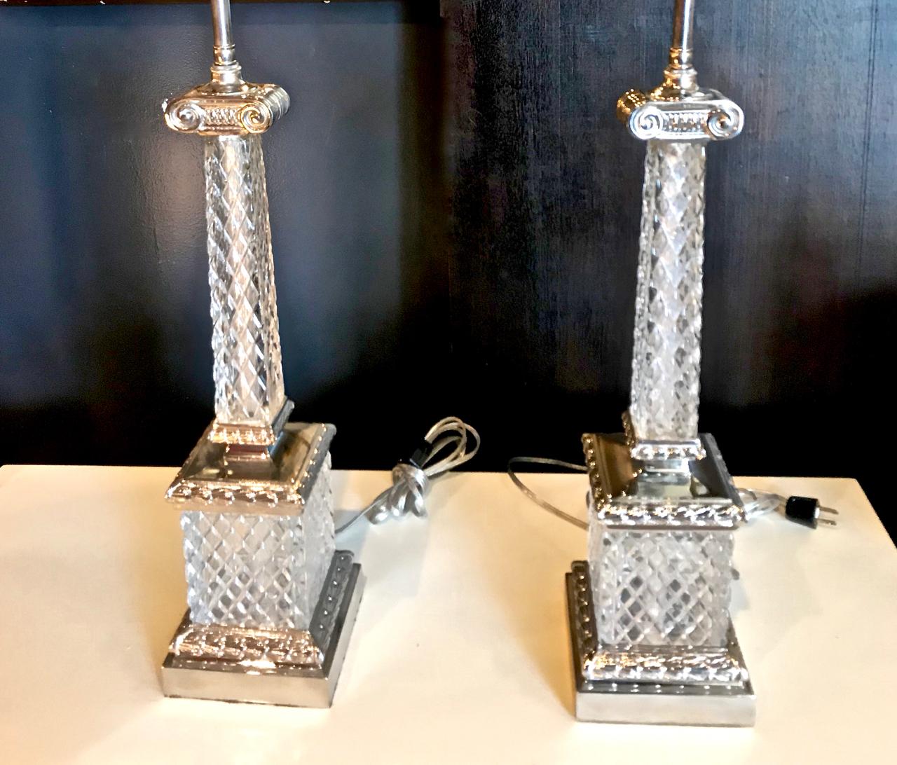 This is a stunning pair of Marbro style cut crystal Ionic column-form lamps that dates to circa 1960. The cut crystal columns are adorned with polished nickel accents brass ionic scrolls and sit on cut crystal and polished nickels plinths. The lamps