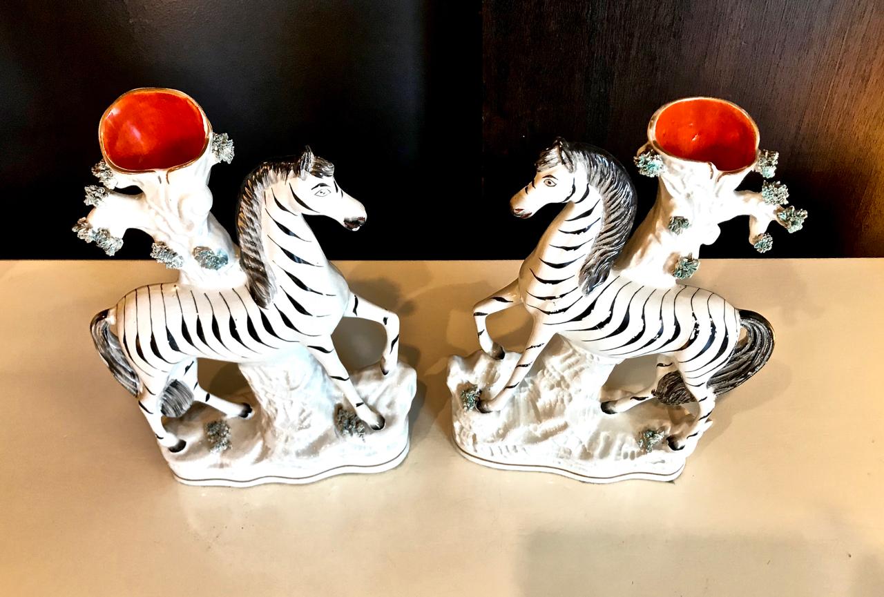 This is a superb pair of opposing zebra Staffordshire spill vases that dates to circa 1880. The opposing zebras are elegantly modeled with minimal decoration, the black and gray tones are highlighted by the simple bright orange-red of the interiors