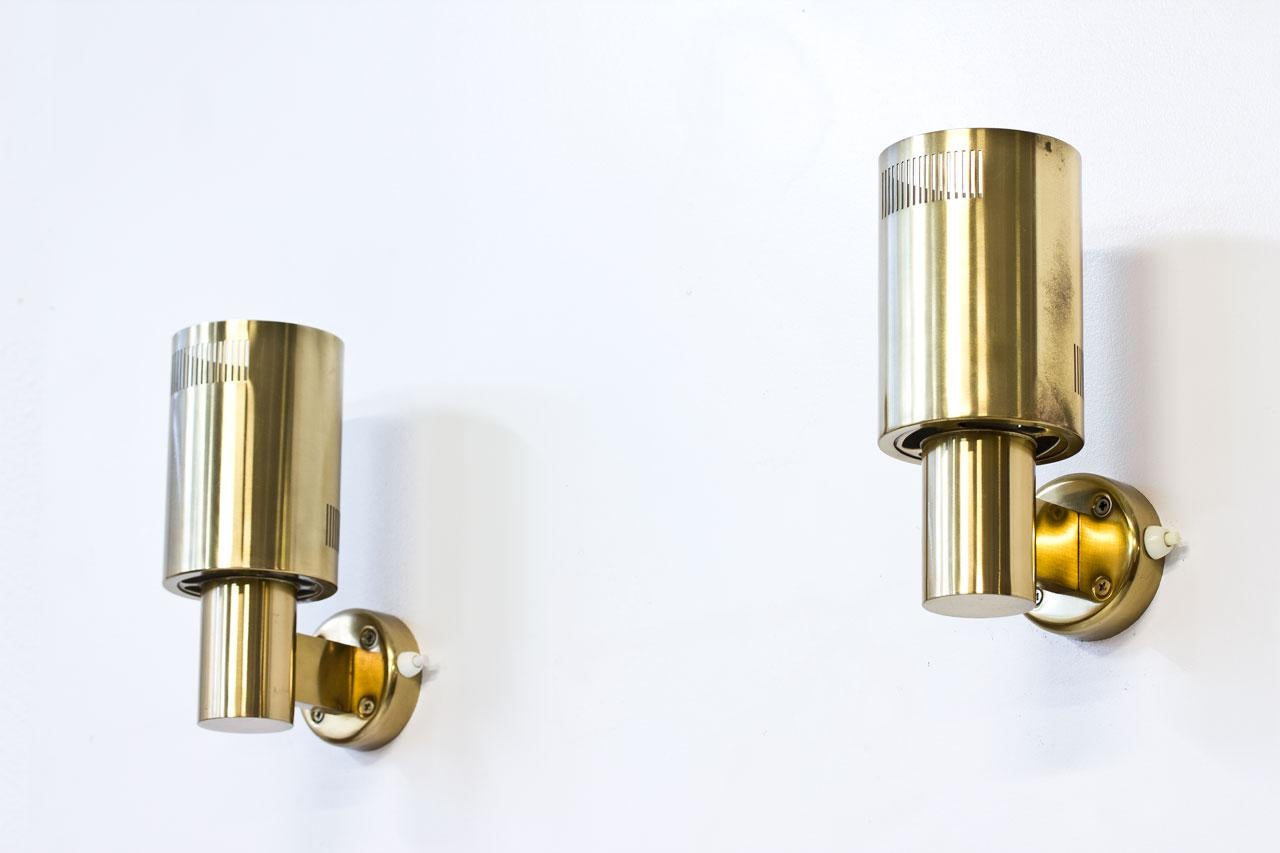 Pair of brass wall lamps by unknown maker, most likely made in Sweden during the 1960s. Can be installed with up or down light, at your convenience. Grey inside reflector. Light switch on base.