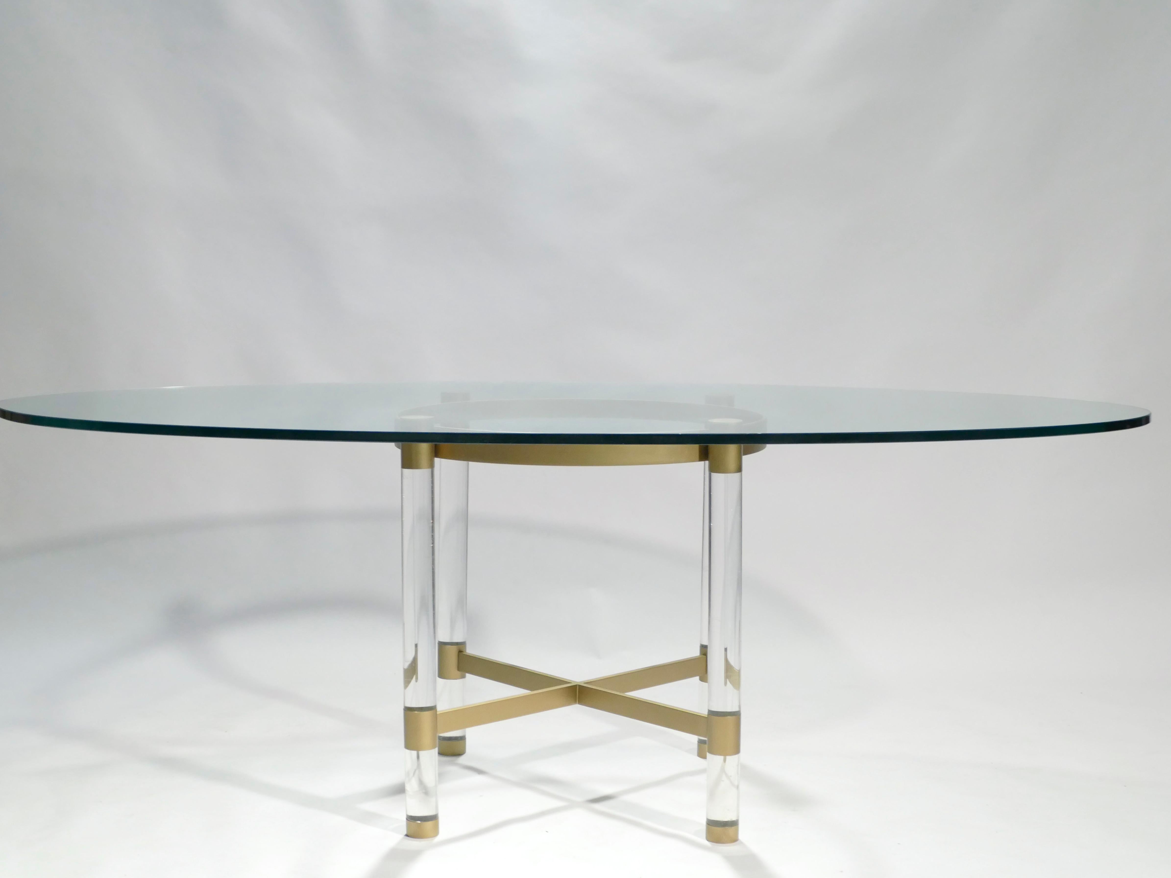 A rare find, this dining table exemplifies the designs by Sandro Petti for company Metalarte around 1970. A thick transparent glass surface has a striking oblong shape and rests atop Lucite and matte brass legs. Four Lucite columns support a brass