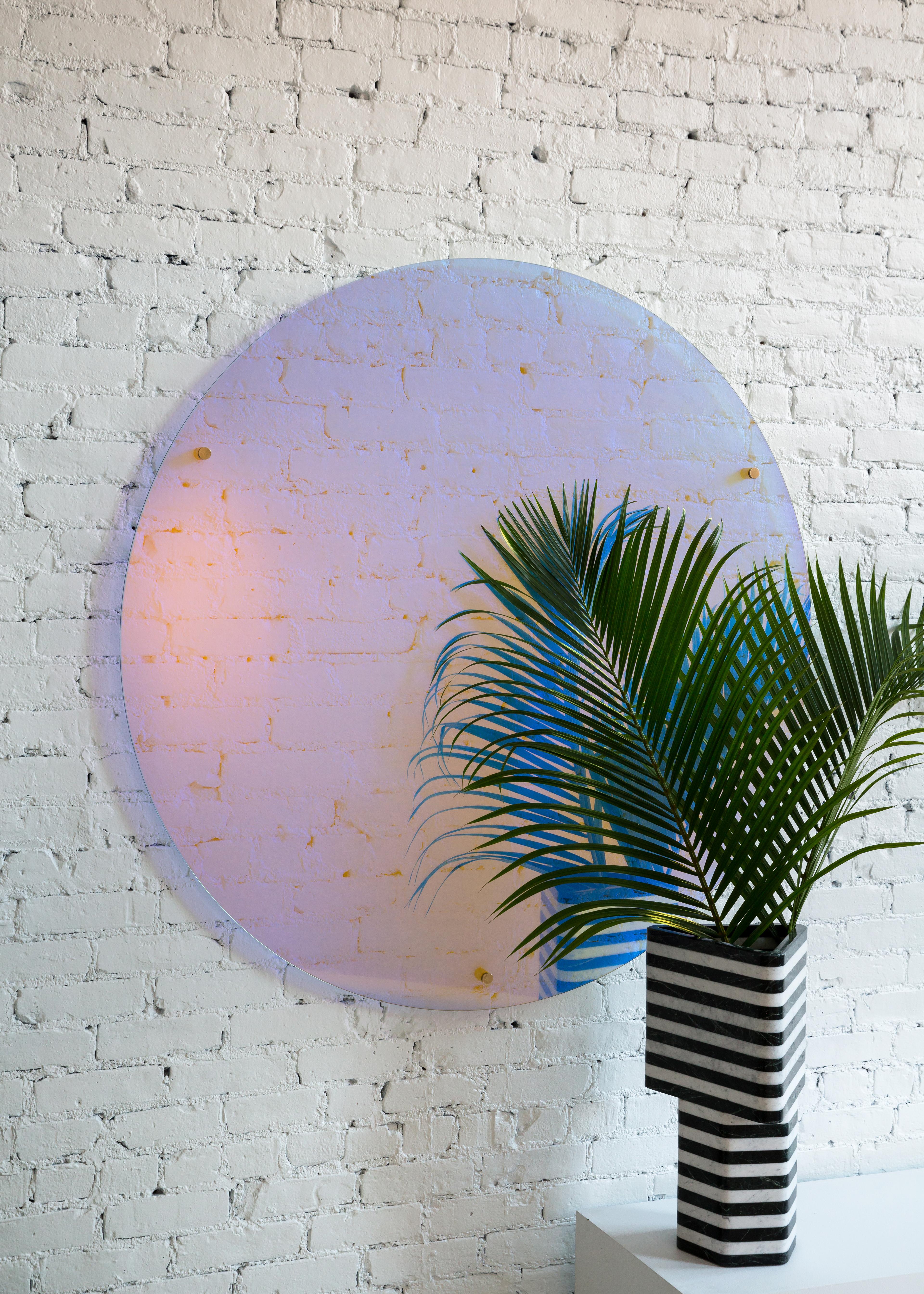 This unique wall mounted piece is as much a statement art piece as it is a mirror. Made of the highest quality dichroic glass the color shifts when viewing from different angles and throughout the day as changes in natural light intensity and color