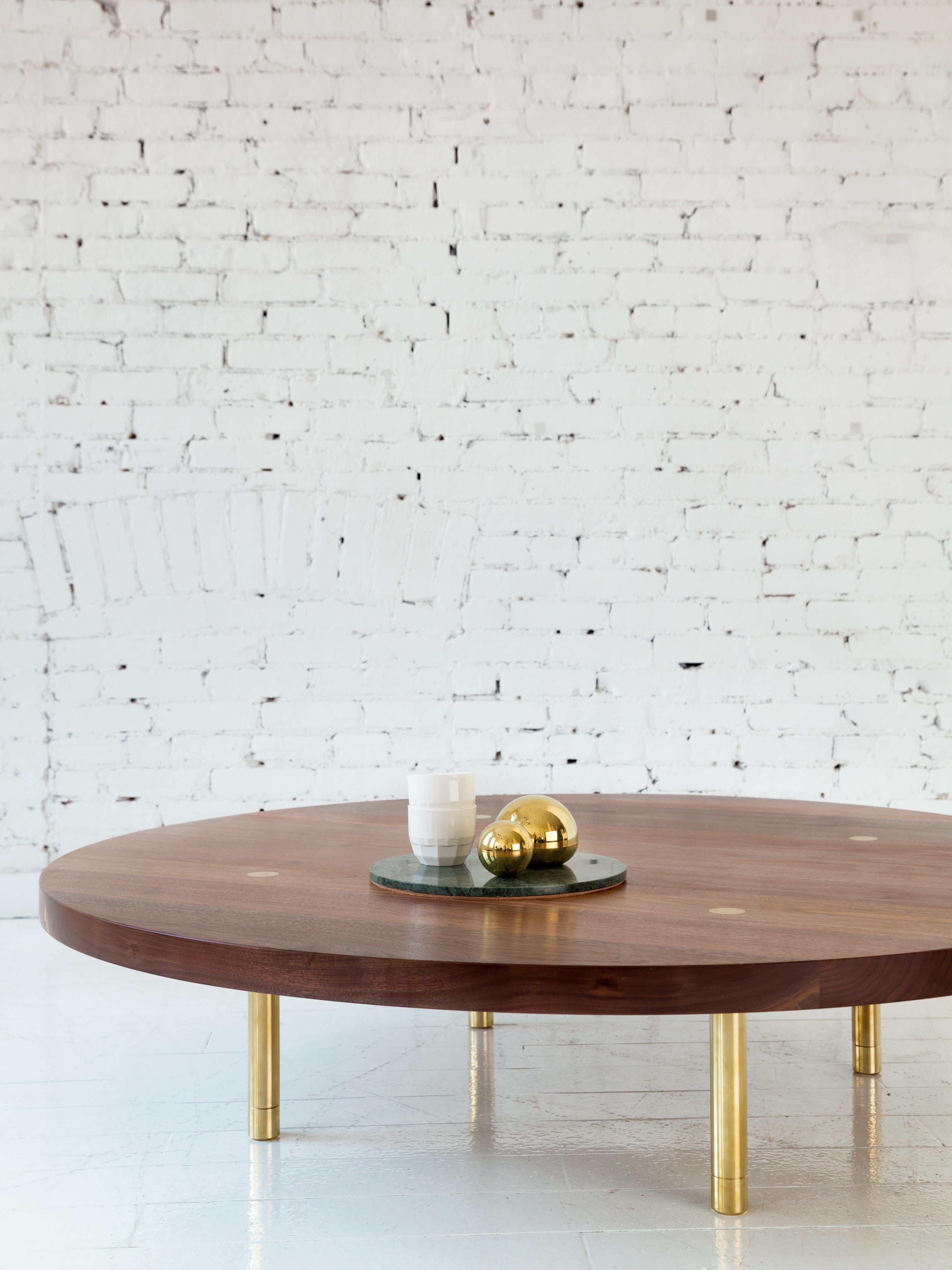 This contemporary, minimal wooden coffee table features a hardwood top and solid brass legs with our signature tenon detail and precision machined leveling feet.

Shown here with a walnut circular top and burnished brass legs.  Made to order in