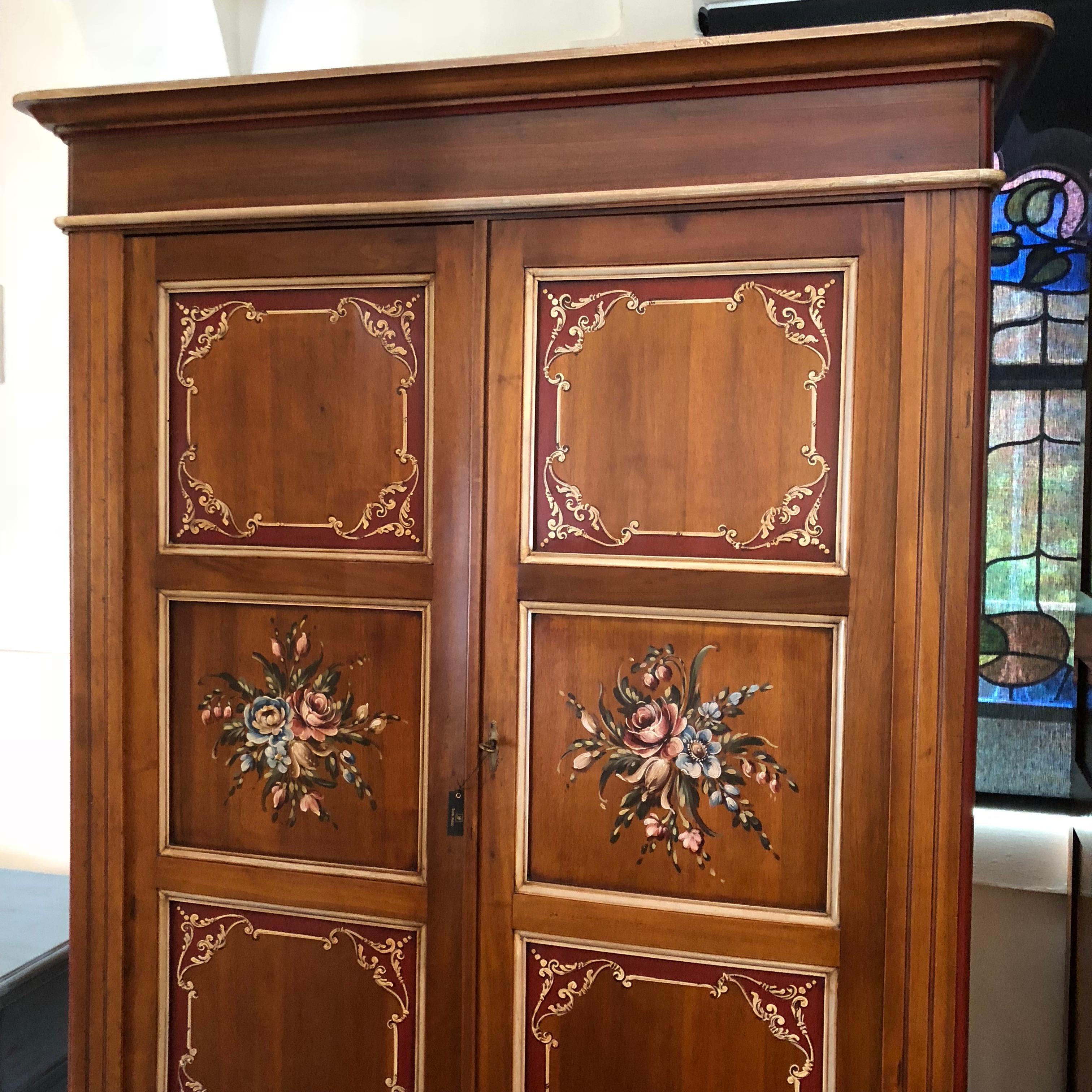 This beautiful Venetian armoire features hand-painted fiore (flowers) to the centre inset panels and hand-painted Venetian scroll frames throughout the front, lower drawer and side panels. This superb piece is made from Italian pine in the late 19th