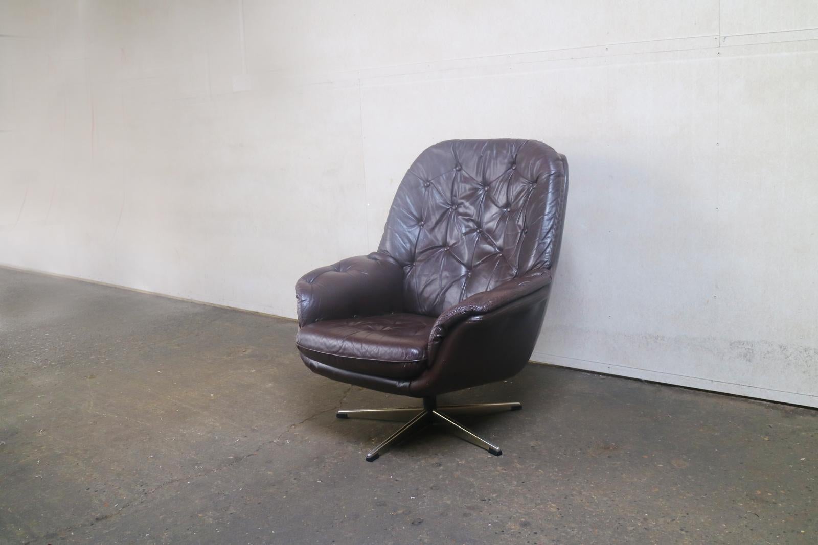 A Danish Mid-Century Modern swivel armchair, with button detailing on seat and backrest, upholstered in the original very dark brown leather.