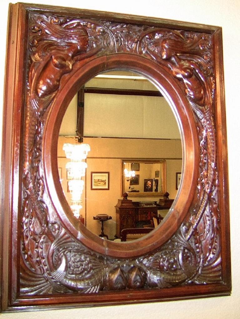 Gorgeous late 19th century American highly carved, dark walnut wall mirror.

The carving on this mirror is simply stunning.

It depicts two mermaids on either side of the oval mirror, with fish and oceanic themes throughout.
Probably made in